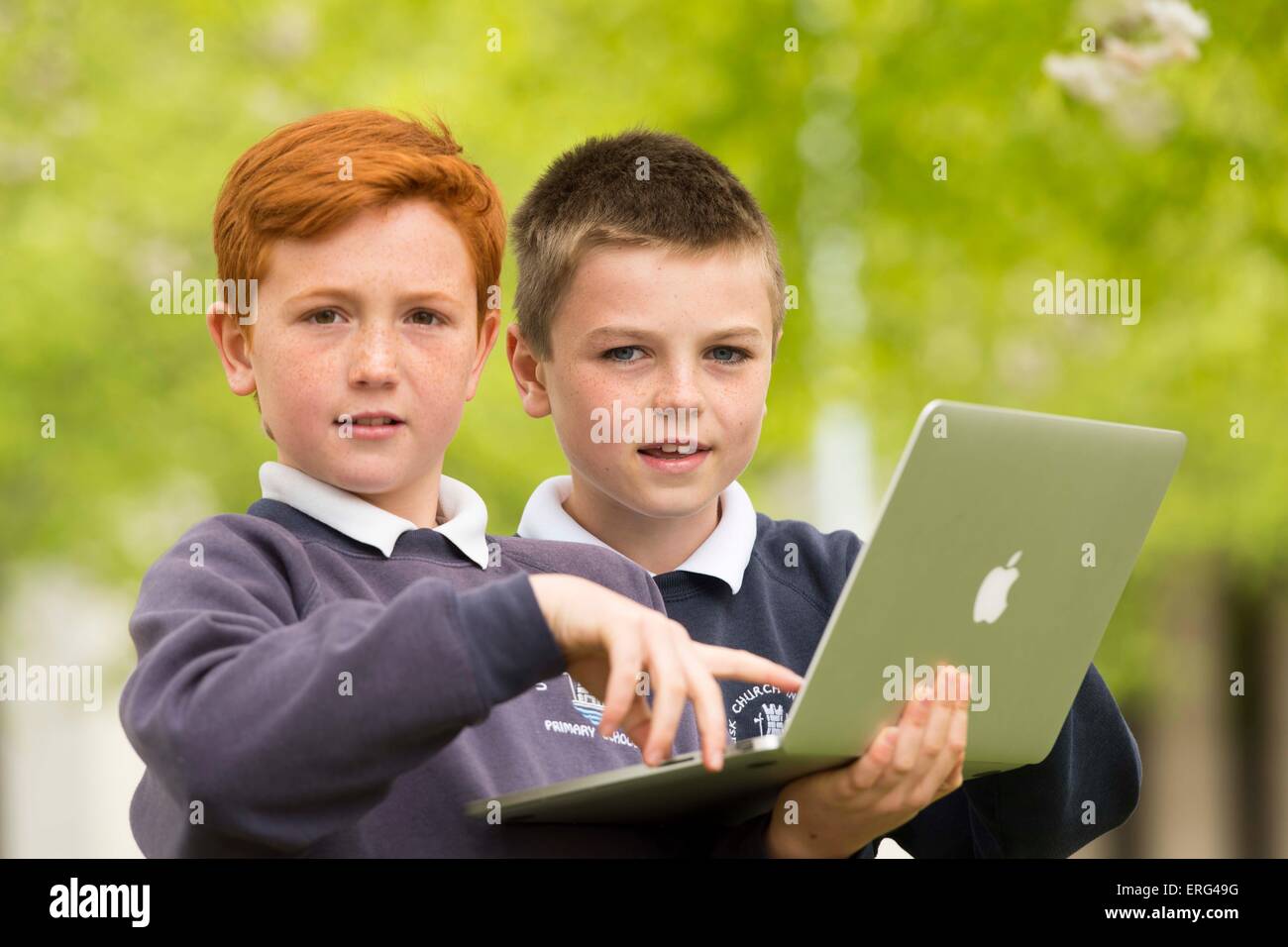 School children learning about technology and computers while outside using laptops. Stock Photo