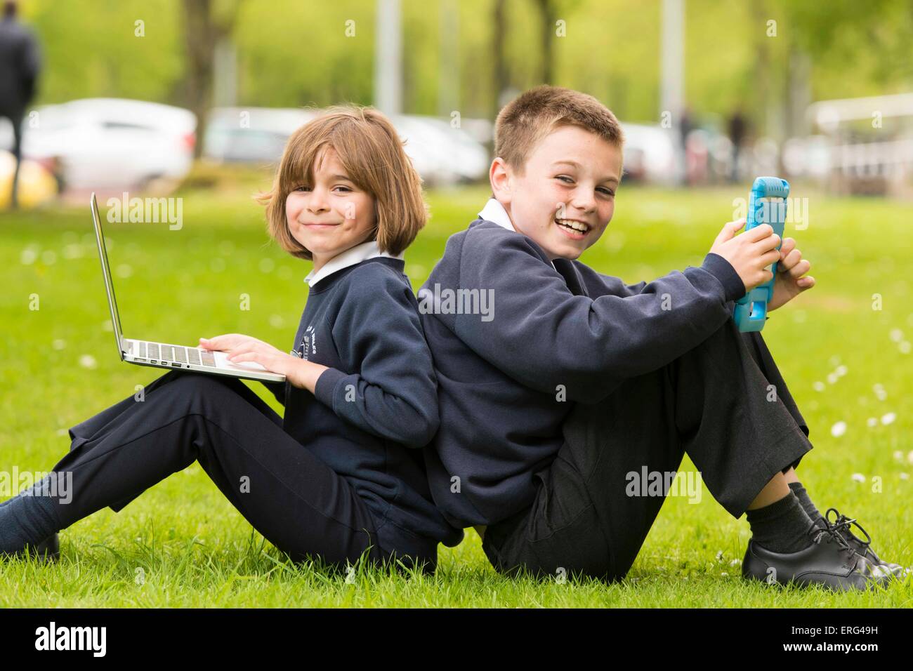 School children learning about technology and computers while outside using laptops. Stock Photo