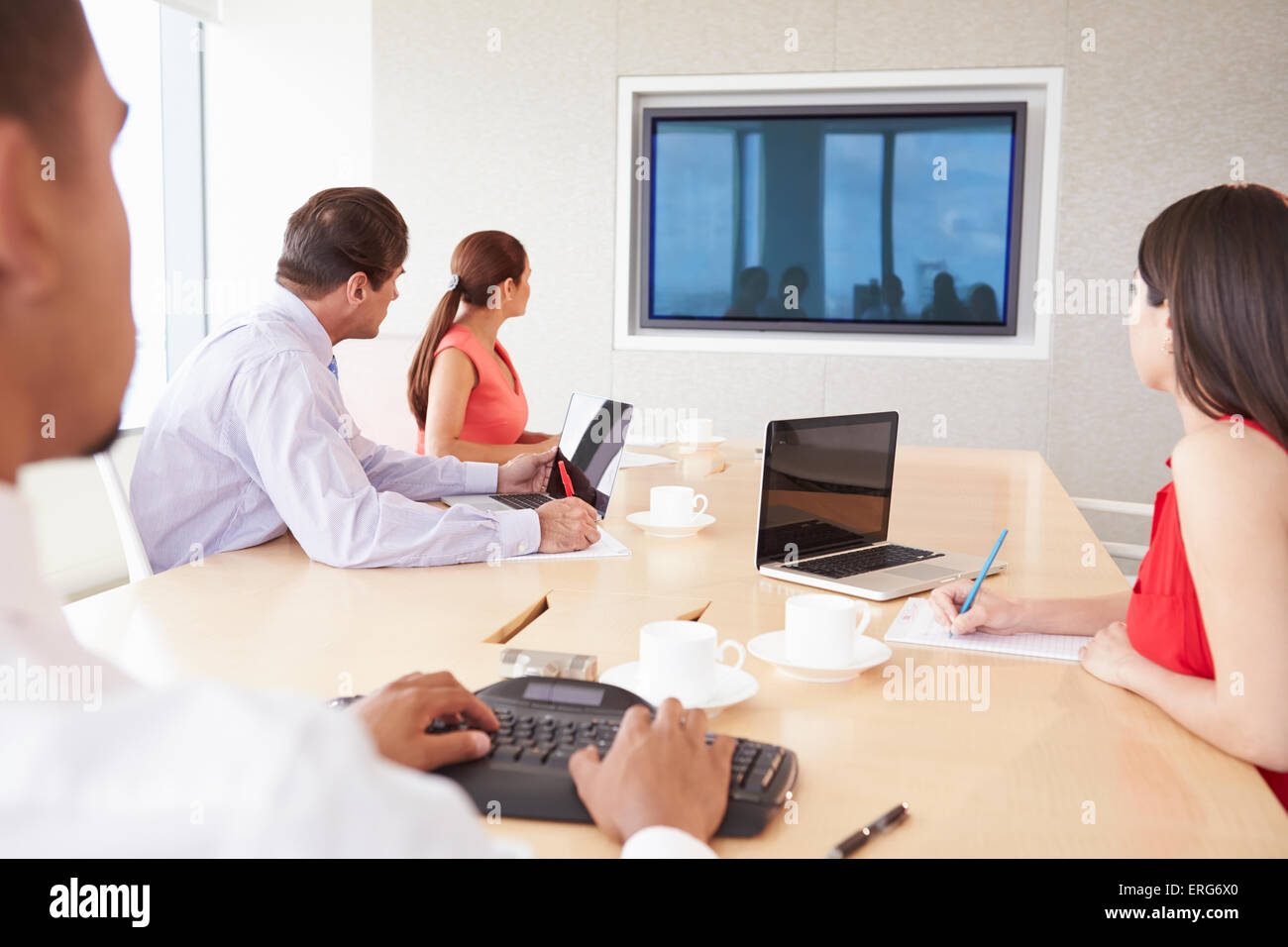 Four Businesspeople Having Video Conference In Boardroom Stock Photo