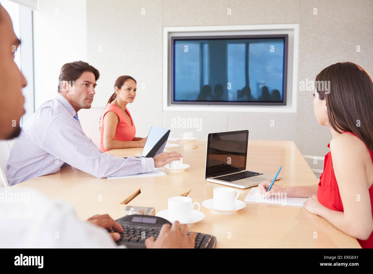 Four Businesspeople Having Video Conference In Boardroom Stock Photo