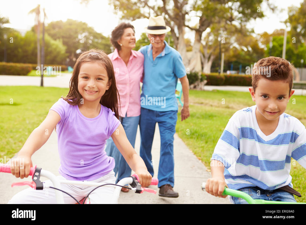Grandparents Taking Grandchildren To Ride Bikes In Park Stock Photo