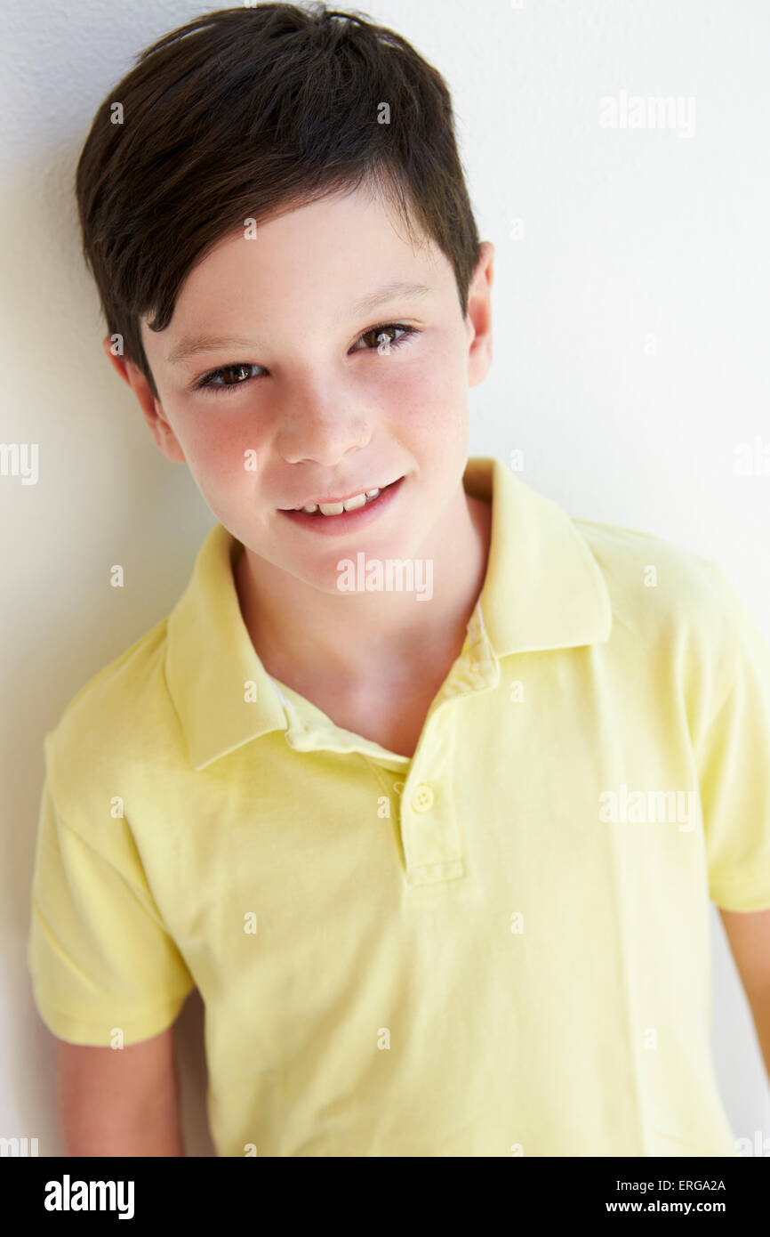 Smiling Young Boy Standing Outdoors Against White Wall Stock Photo