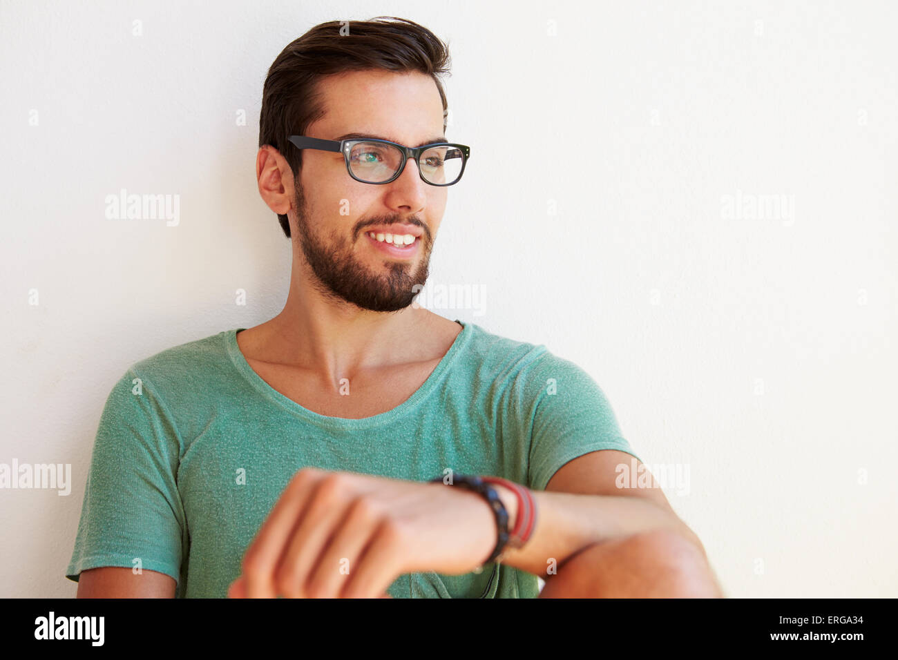 Portrait Of Young Man Sitting Against White Wall Stock Photo