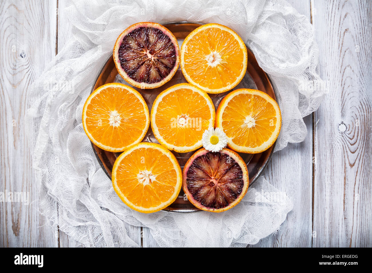 Cut Oranges on the round shape plate at white wooden background Stock Photo