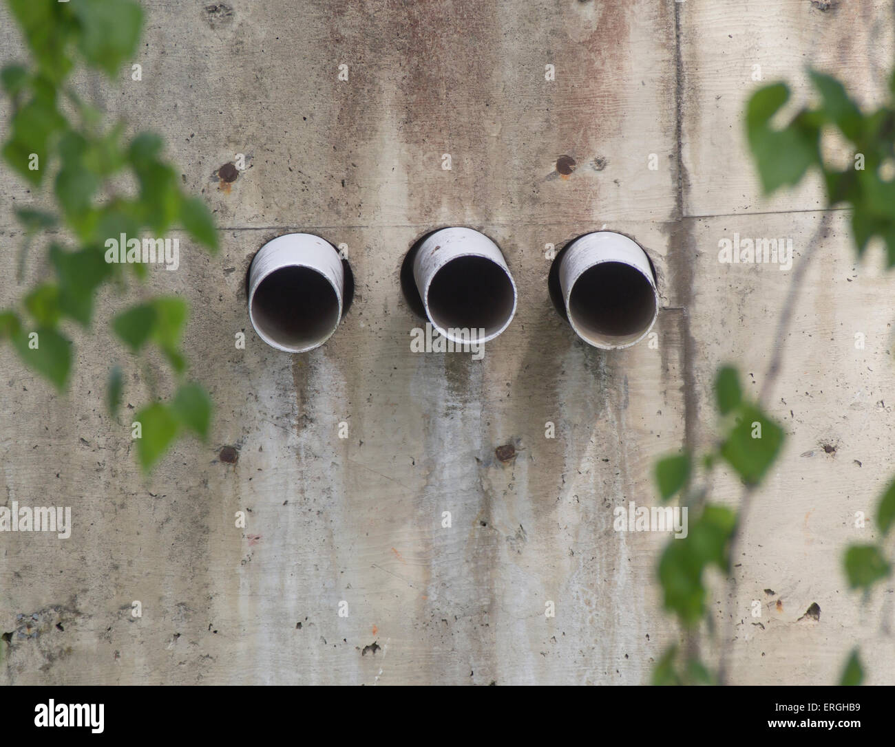 Three small drain pipes protruding from a concrete wall Stock Photo