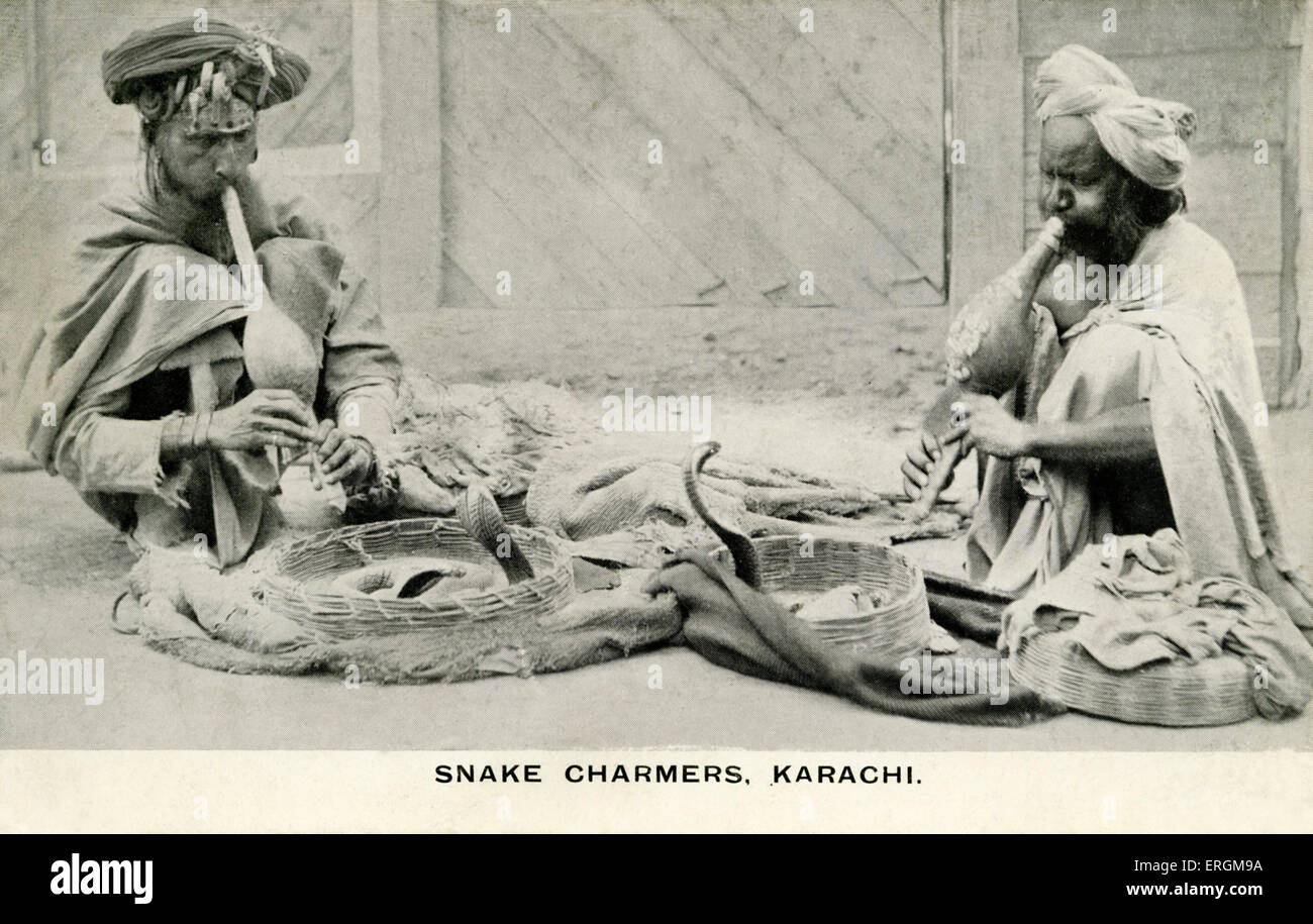 Snake charmers in Karachi, Pakistan. Photograph from early 20th century. Two men play pipes, in two baskets two cobras rise from the ground. Stock Photo