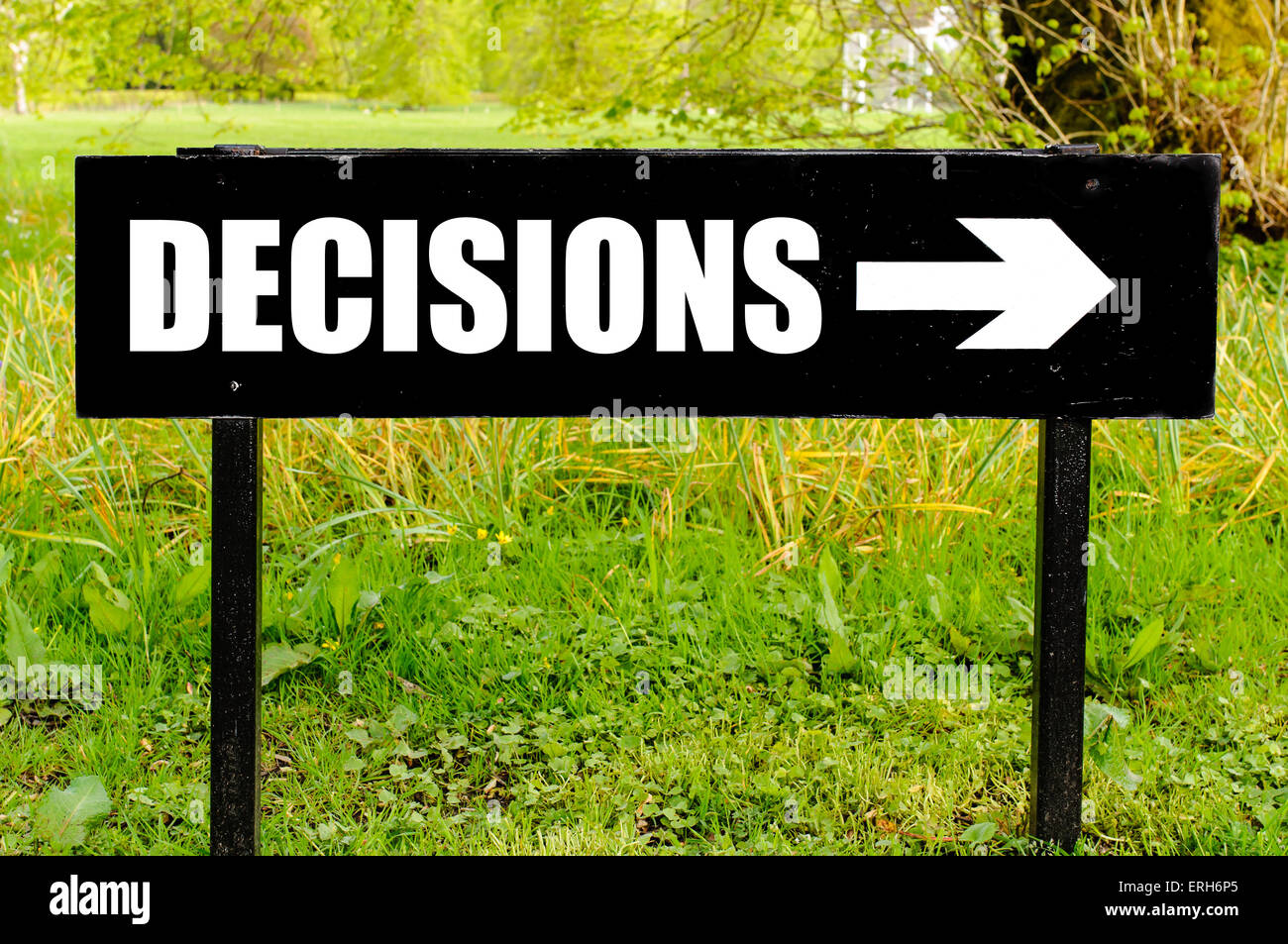 DECISIONS written on directional black metal sign with arrow pointing to the right against natural green background. Concept image with available copy space Stock Photo