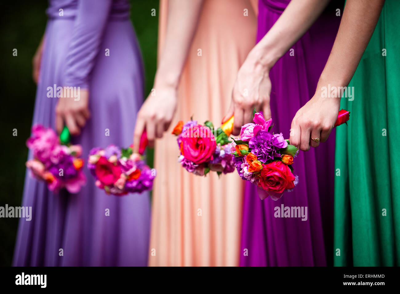 Bridesmaids in colorful dresses with bouquets of flowers Stock Photo