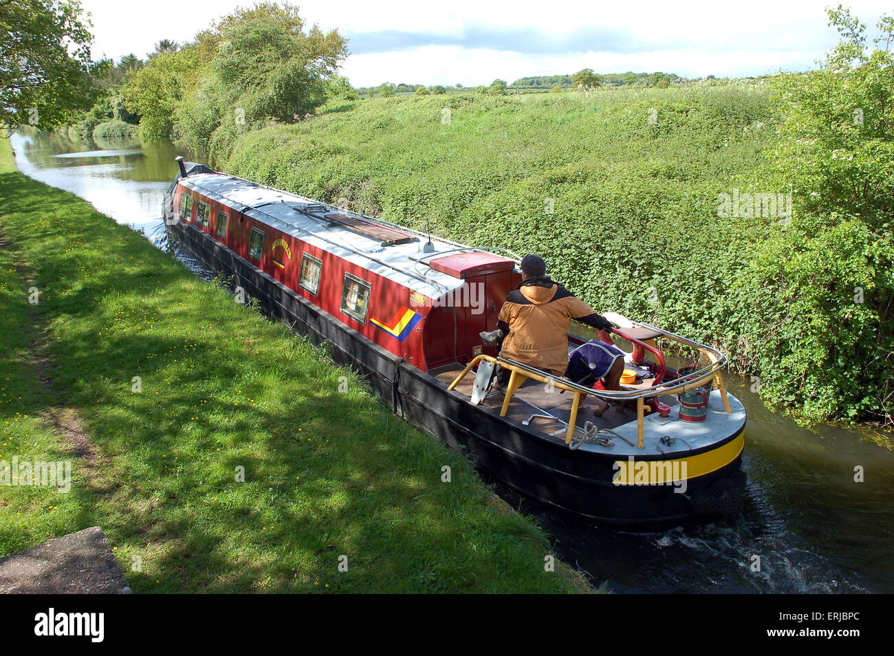 A red narrowboat travels down The Shropshire Union Canal Stock Photo