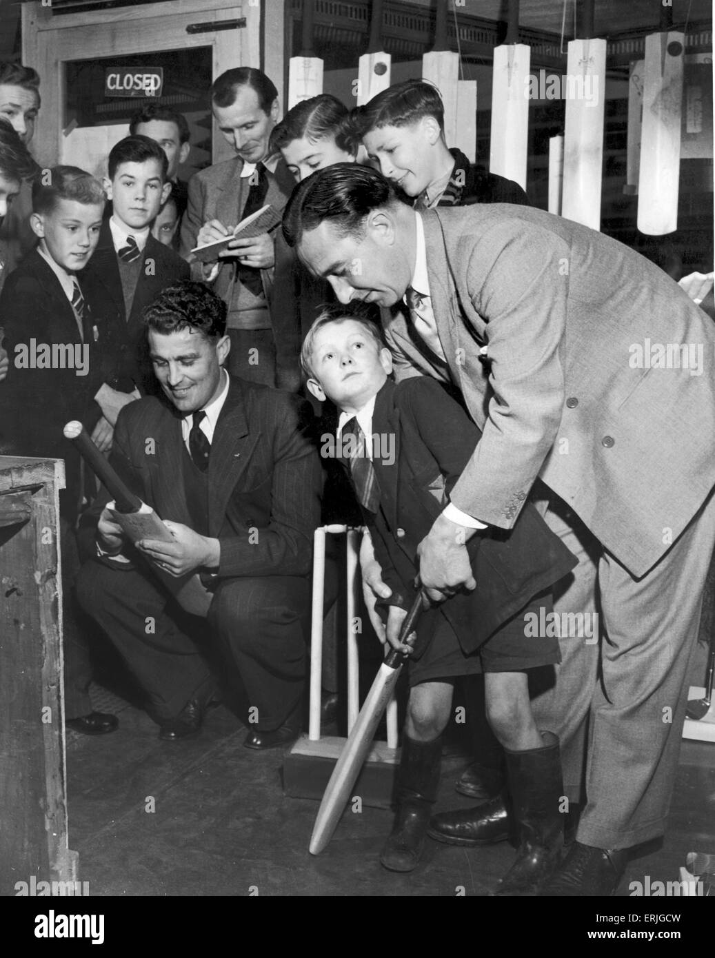 Denis Compton shows five year old Robin Lawrie the best way to hold a cricket bat after he walked into Arsenal footballer Wally Barnes store in Haringay, London.  3rd May 1950. Stock Photo
