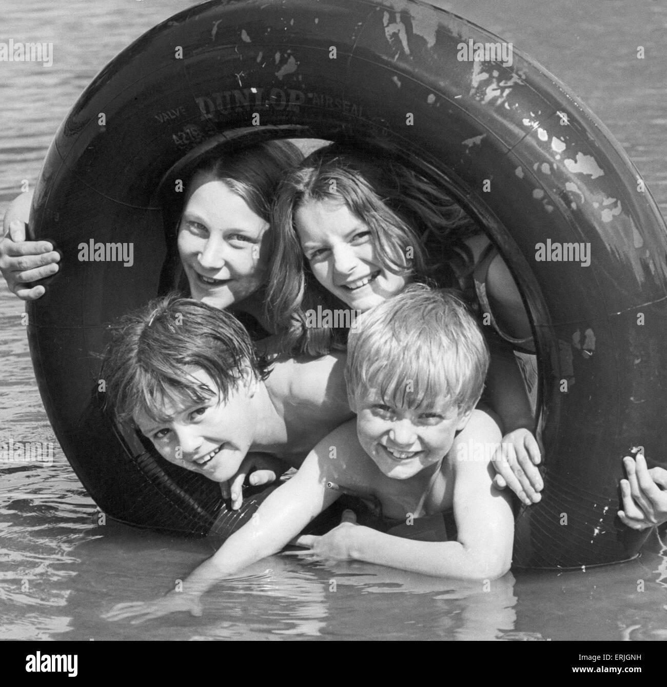 Water, sun and an old tyre...what more could one ask? Having fun at Binley Road paddling pool, Coventry, are (top left) Julie Packer 12, and Brenda Medforth 12 and (lower left) David Medforth 11 and Andrew Muller 8. 5th August 1977 Stock Photo