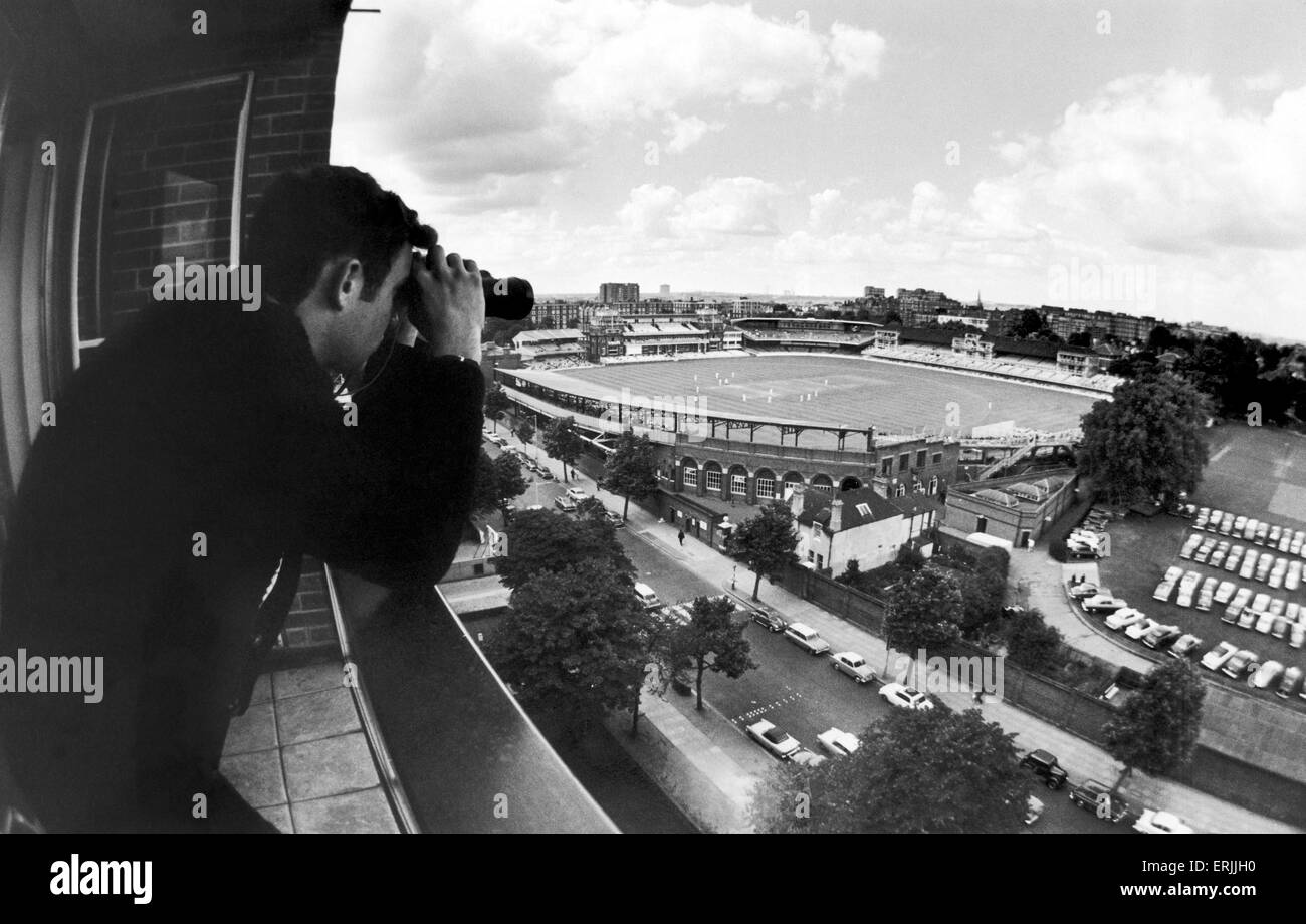 New view of Lords cricket ground on the first day of cricket on Sunday. Jonathan Cree, son of Dr Cree, views he cricket through binoculars from the balcony of his father's ninth floor flat in a block called Lords View. 1st August 1965. Stock Photo