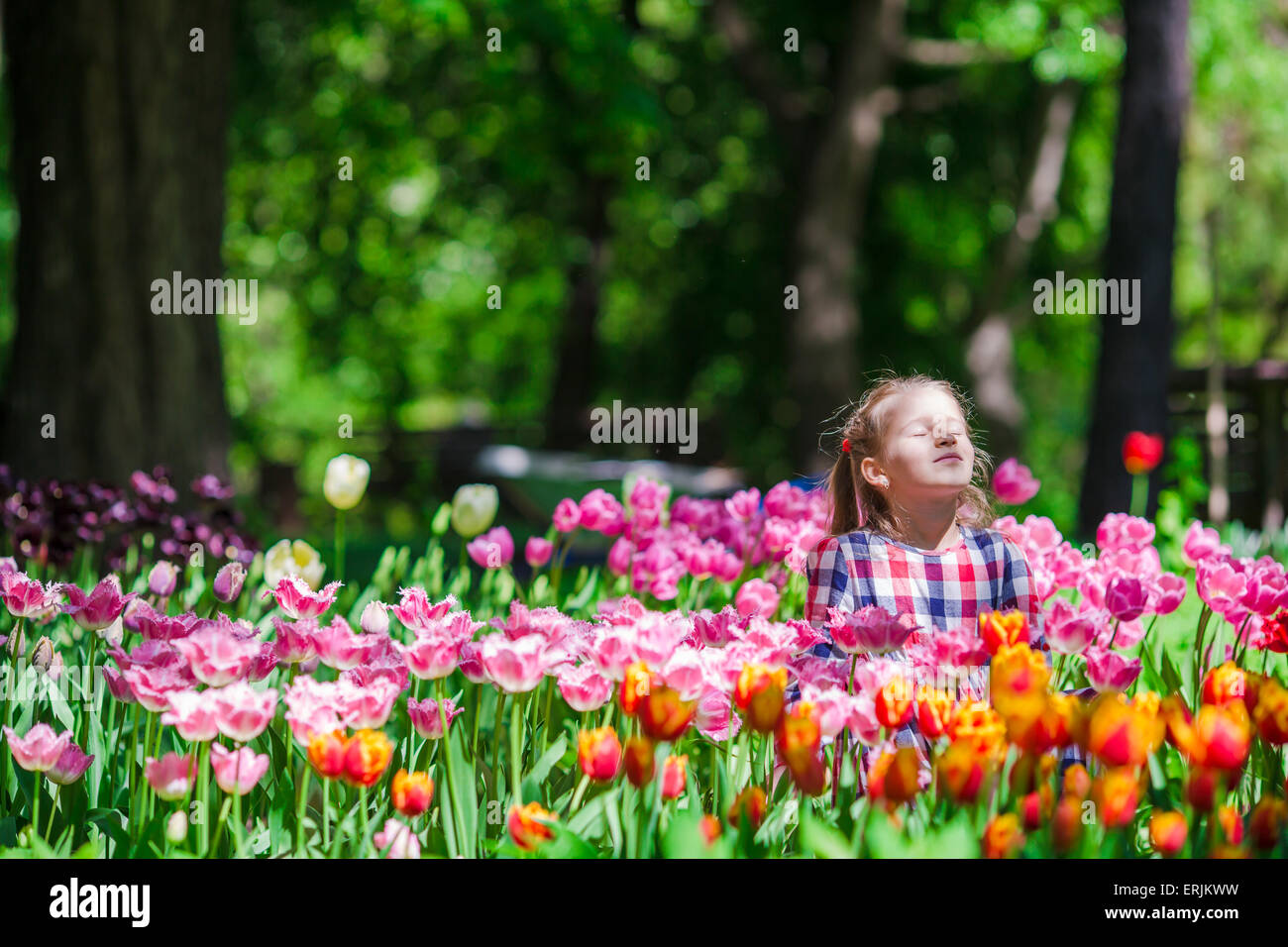Little adorable girl in the lush garden of tulips Stock Photo - Alamy