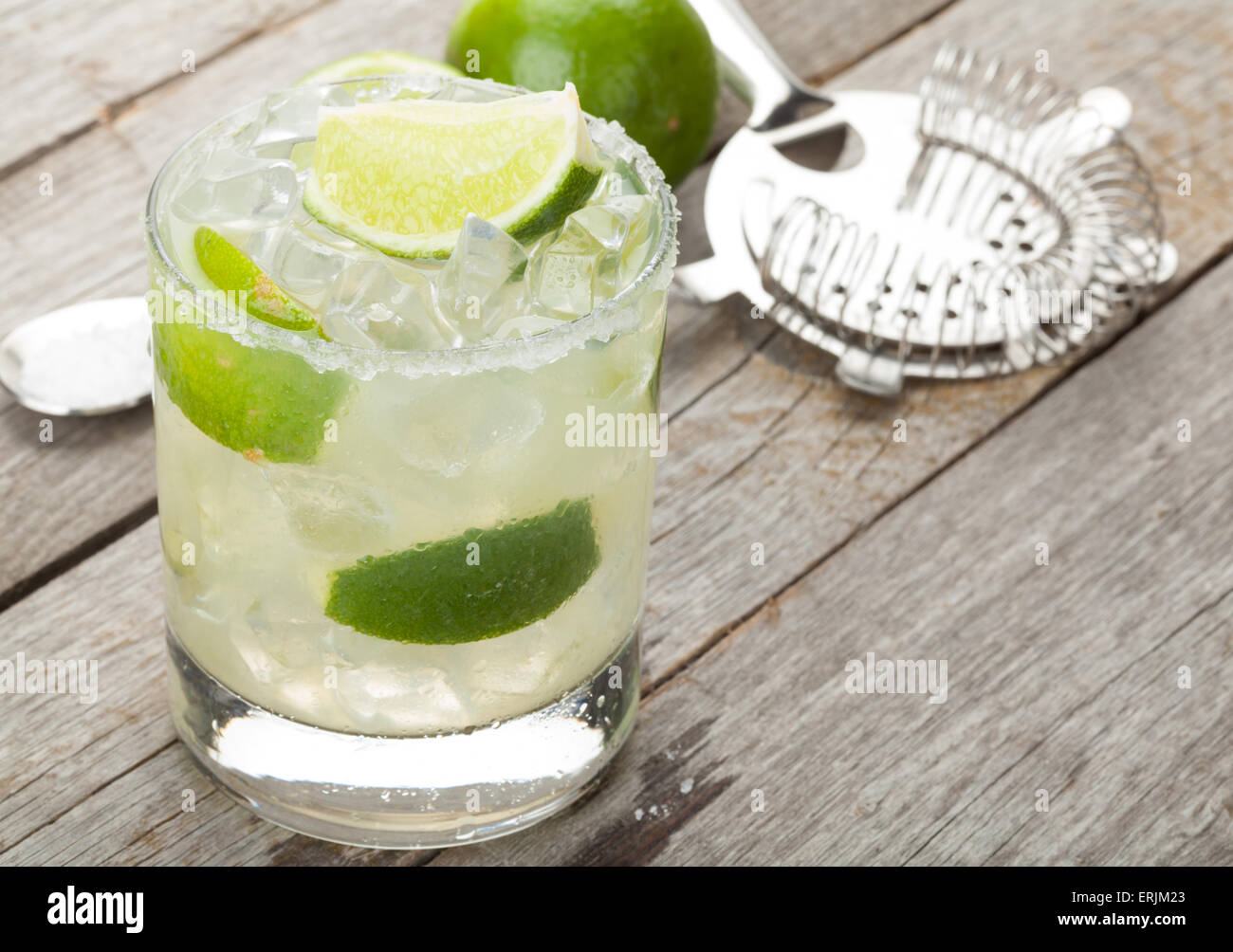 Classic margarita cocktail with salty rim on wooden table with limes ...