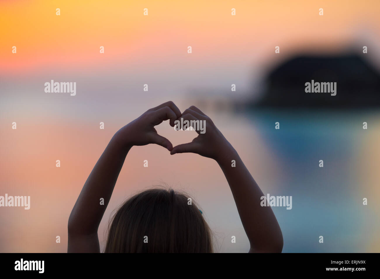 Silhouette of heart made by kids hand at sunset Stock Photo