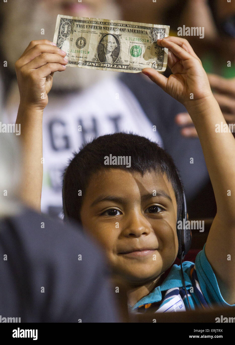 Los Angeles, California, USA. 3rd June, 2015. David Lazo, 5, raises a dollar bill as supporters await the Los Angeles City Council's vote an ordinance to raise the minimum wage in the city to $15 an hour by 2020 in Los Angeles. The City Council voted 13-1 to raise the minimum wage in Los Angeles to $15 an hour by 2020, but a second vote is required for final approval because the tally was not unanimous. If given final approval and signed by Mayor Eric Garcetti, the city, with 3.8 million residents, would become the biggest in the country with a $15 minimum wage. © ZUMA Press, Inc./Alamy Live N Stock Photo
