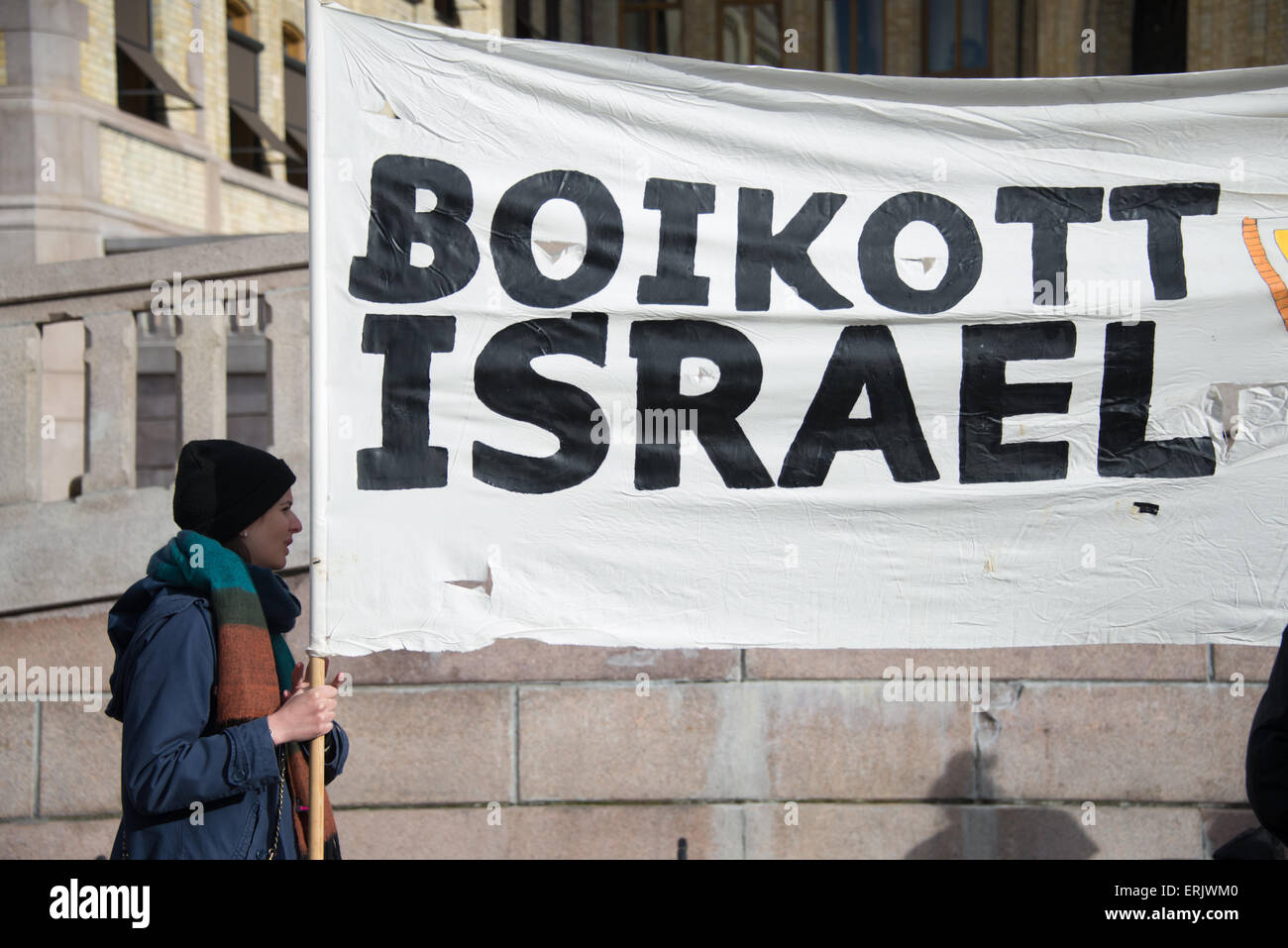 An activist holds a banner reading 'Boycott Israel' during a protest in front of the Norwegian Parliament building. Stock Photo