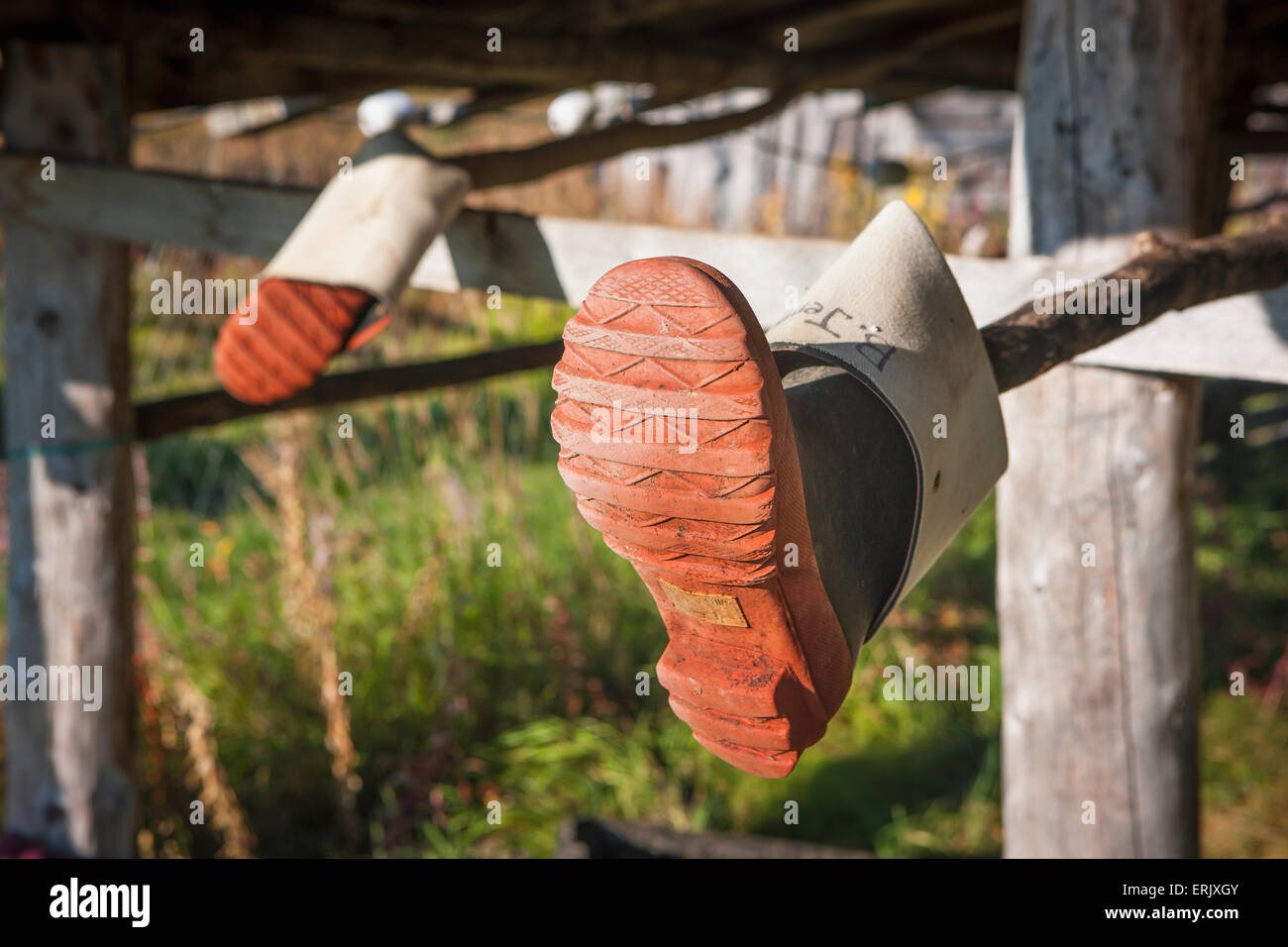 Rubber boots hung outdoors on log fish rack, Shungnak, Arctic Alaska
