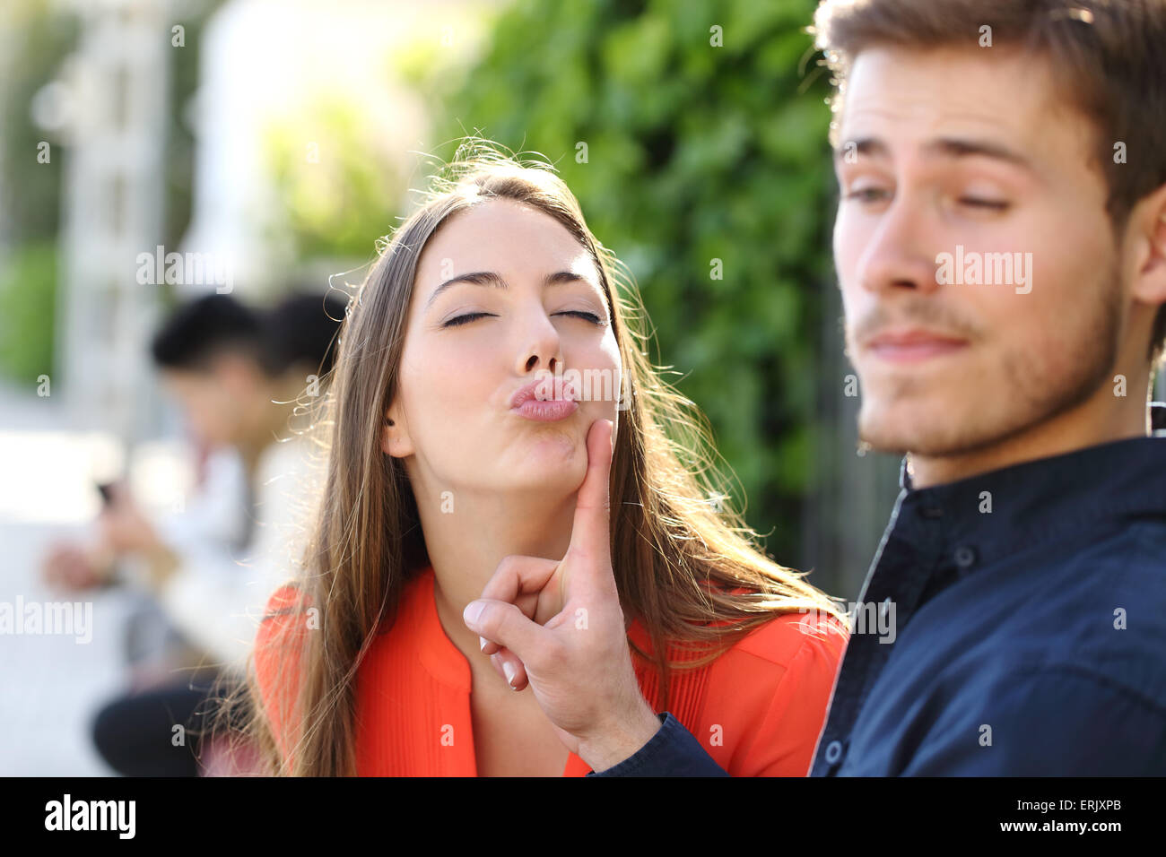 Woman trying to kiss a man and he is rejecting her outdoor in a park Stock Photo