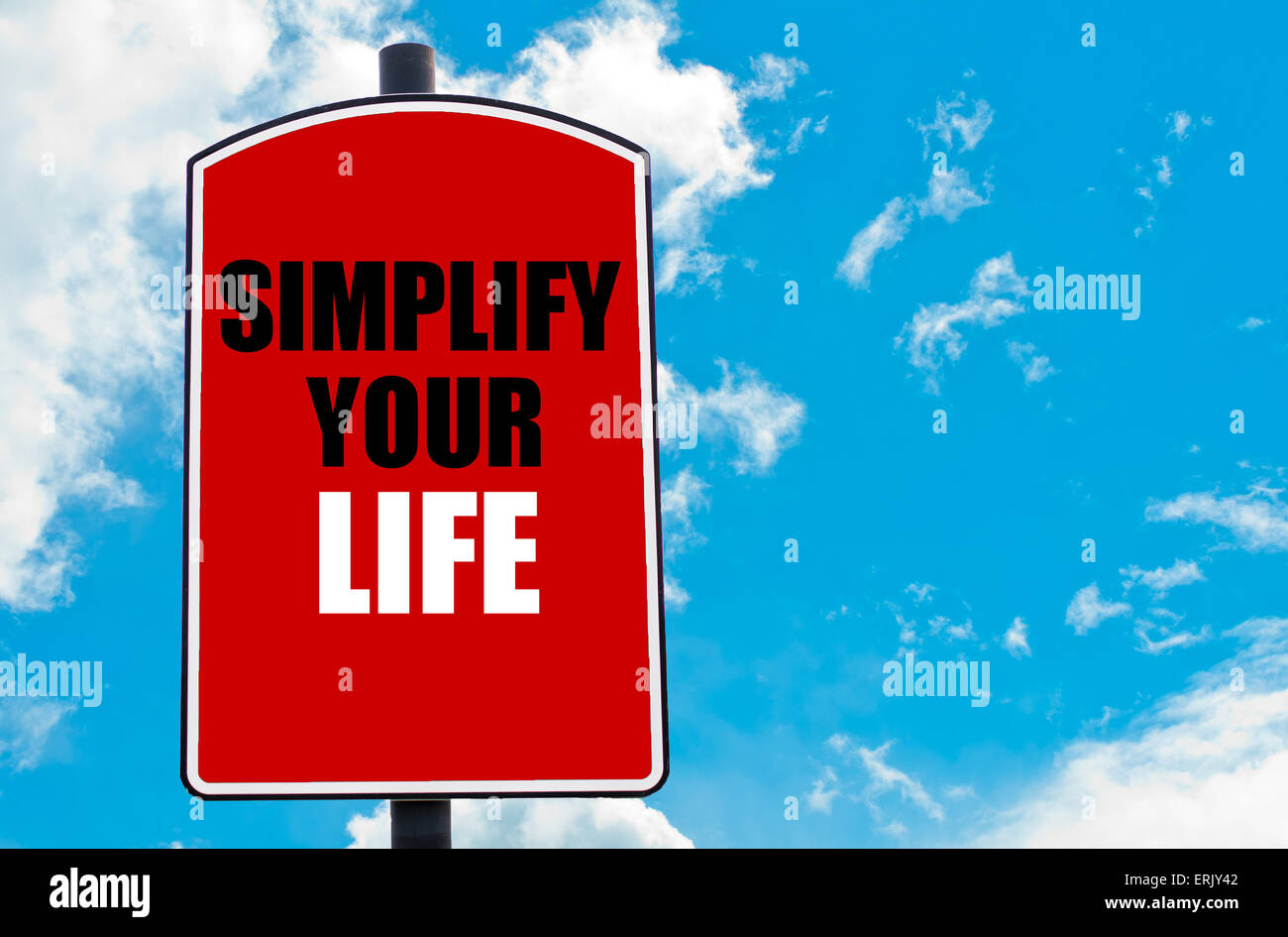 Simplify Your Life  motivational quote written on red road sign isolated over clear blue sky background. Stock Photo