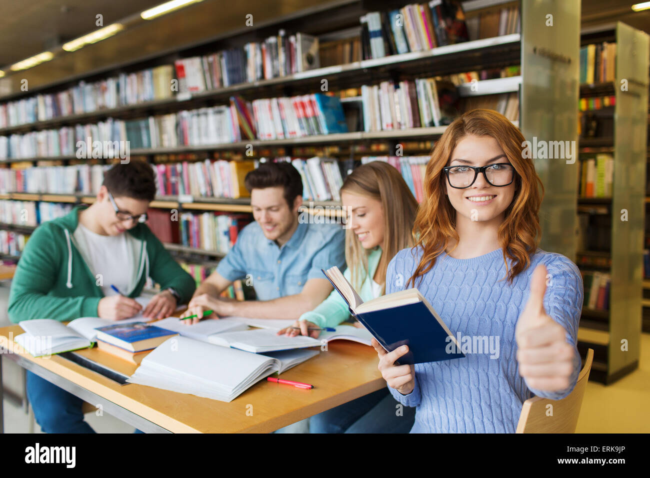 happy student girl showing thumbs up in library Stock Photo - Alamy