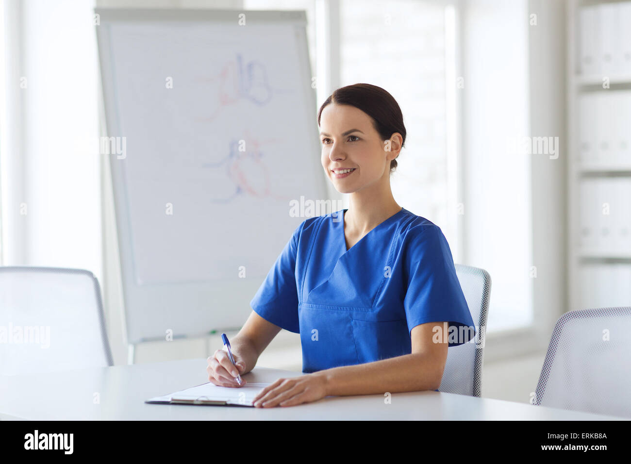 happy female doctor or nurse writing to clipboard Stock Photo - Alamy