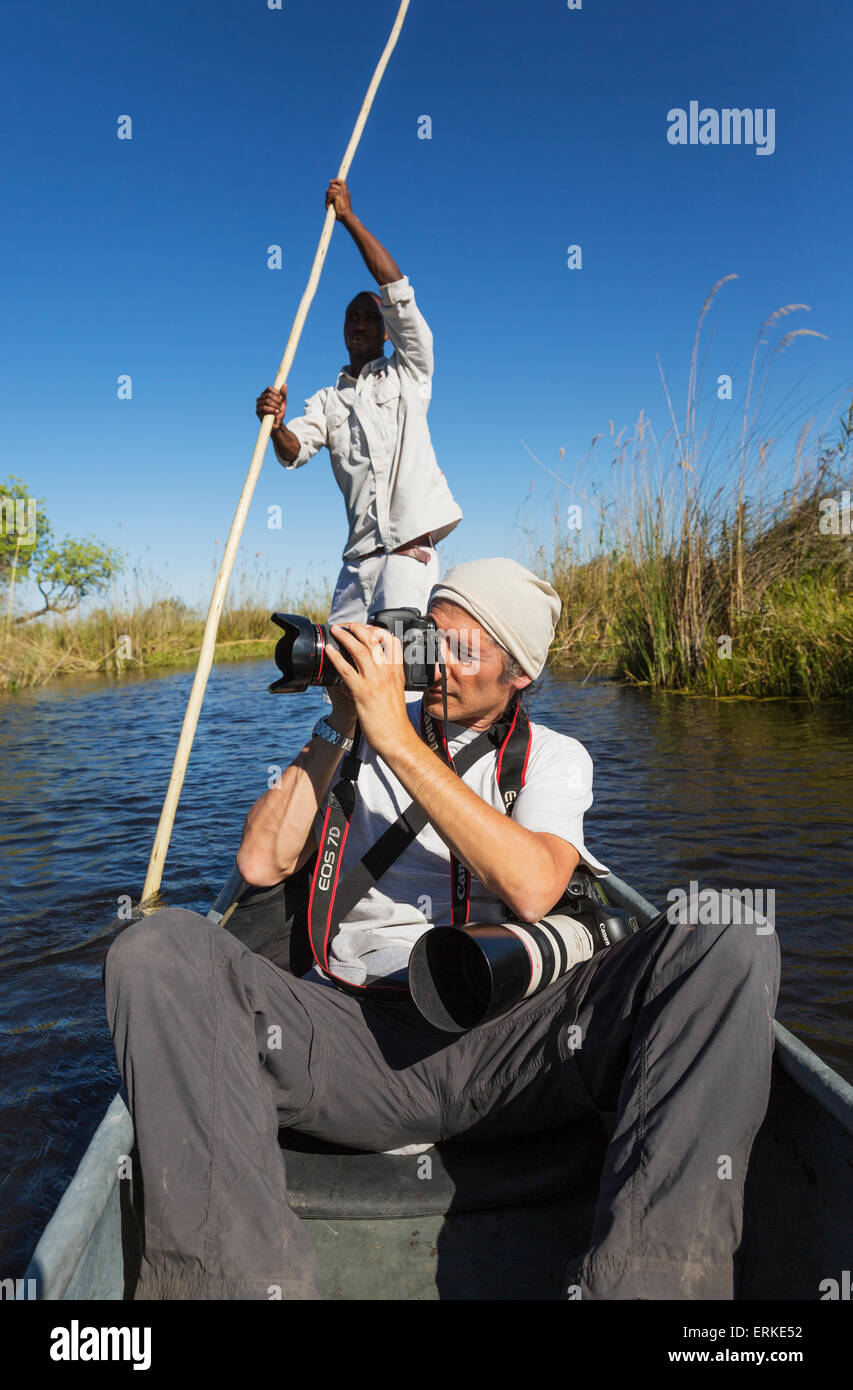 Game viewing safari, photographer in a traditional Mokoro boat, Okavango Delta, Moremi Game Reserve, Botswana Stock Photo