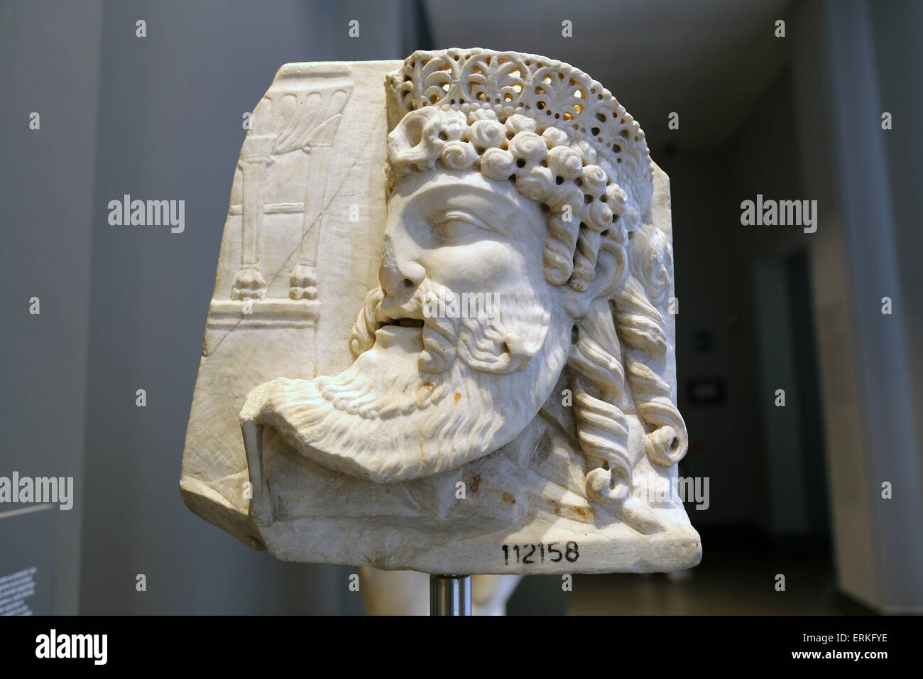 Roman relief. Mask of a deity wearing a crown in archaizing style and a tripod in the background. 1st c. AD. Rome. Stock Photo