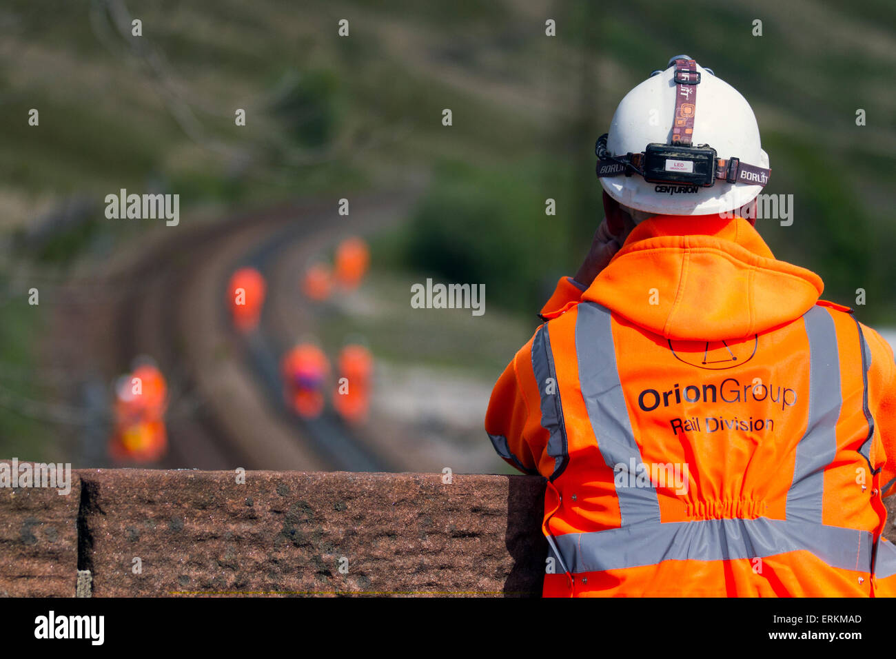 Orion Group Rail Division contractors in Tebay, Cumbria, UK June, 2015. Health and Safety observer for Men at Work. Network Rail Engineers on Settle Carlisle Line, working on rail track maintenance, rail engineer.  Inspectors, Safety engineers, employees, rail workers, workmen, renewing railway lines and Infrastructure surveyors inspecting & measuring the transport freight line track at the summit of Ais Gill. The railway's summit at 1,169 feet (356 metres) is north of Garsdale is the highest mainline in England,  and carries heavily loaded main line freight trains. Stock Photo