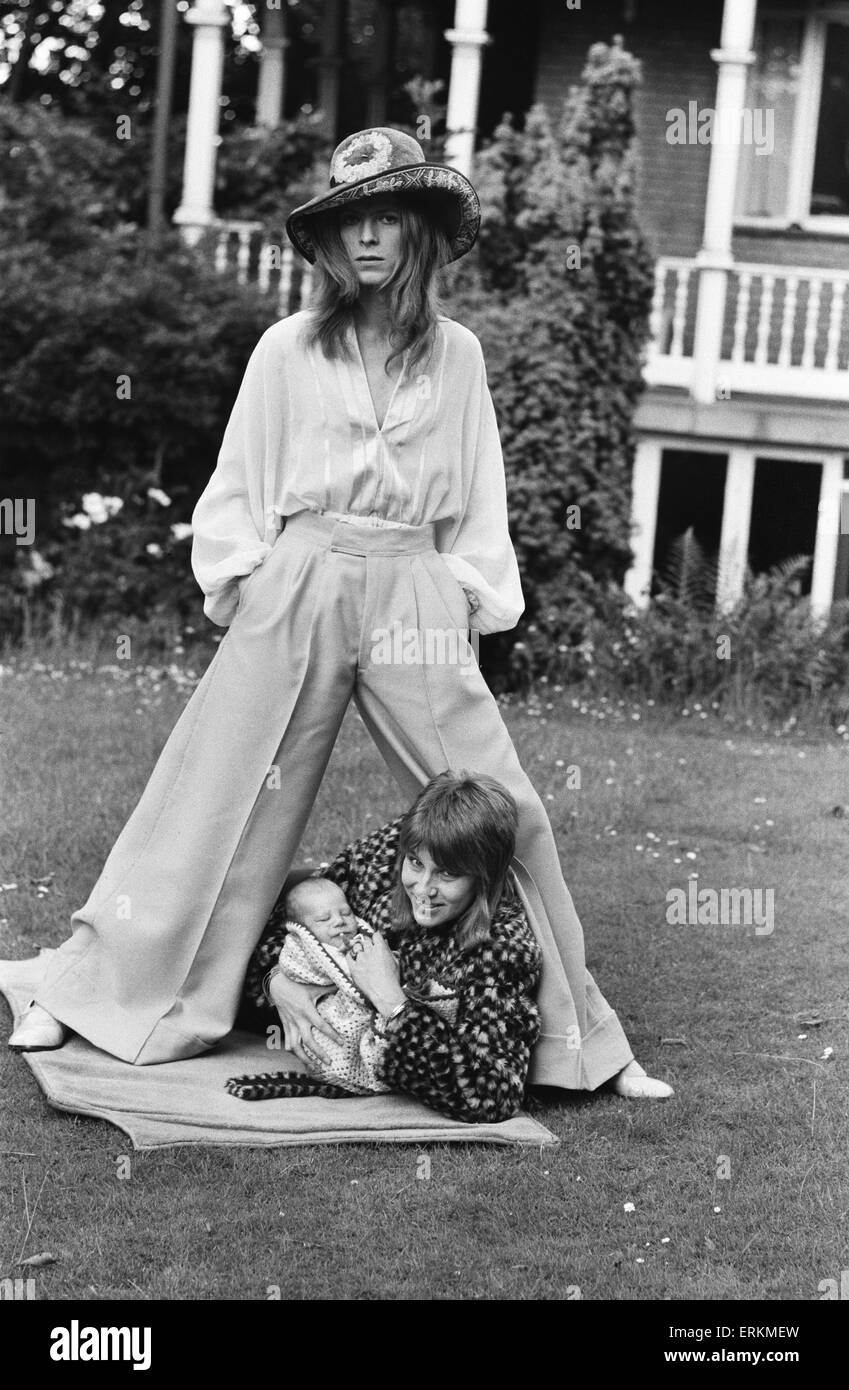 David Bowie, the pop star and song writer, whose wife Angie three weeks ago presented him with a baby boy, which they have called Zowie. Here he is pictured with his family, wearing 44 inch Oxford Bags in pink seaside gaberdine. His shirt is Turkish cotton with a soft felt floppy hat.  29th June 1971. Stock Photo