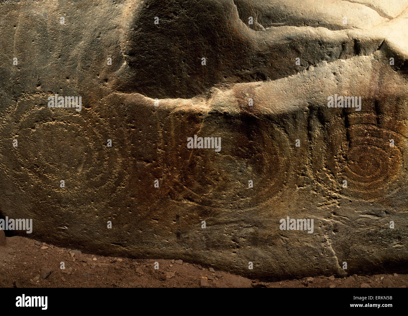 Pecked spiral carvings on the rear slab (stone 8) of E burial chamber inside Barclodiad y Gawres Neolithic passage grave, Anglesey. Stock Photo