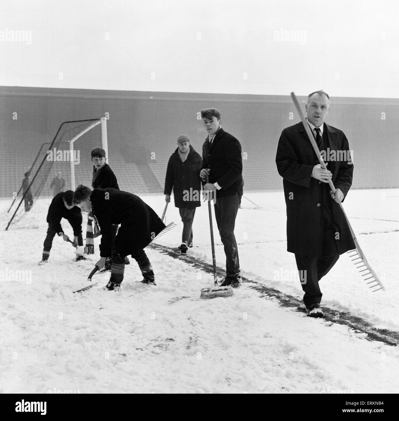 Liverpool manager Bill Shankly helps to clear the snow from the goal line on the Anfield pitch as they prepare for the upcoming fixture against Sunderland. 28th December 1964. Stock Photo