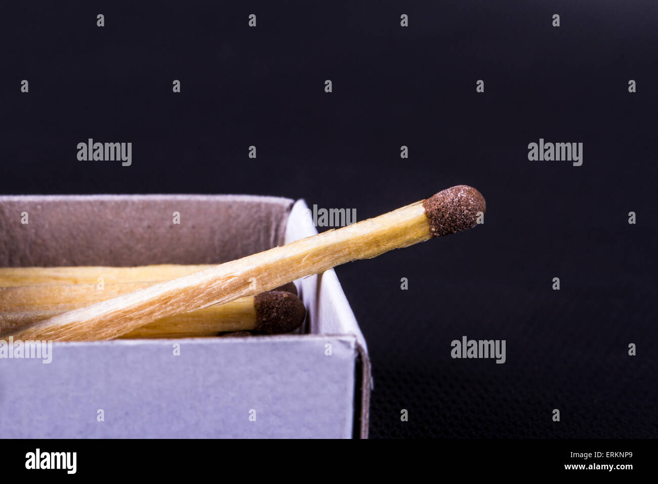 Close up detailed front view of a match in a matchbox, on black ...