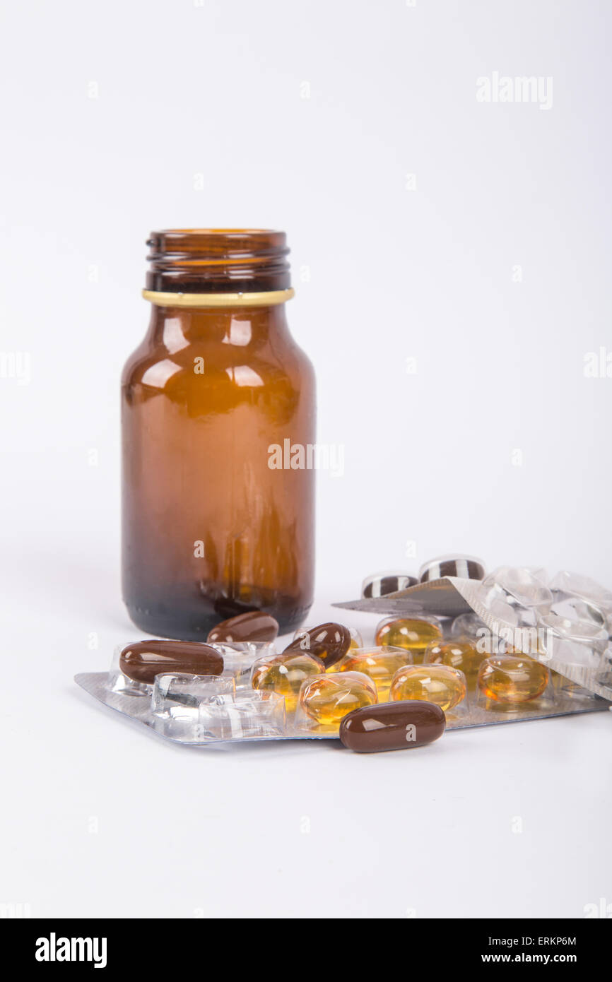 Close-up view of mix of pills and standing brown glass medical bottle ...