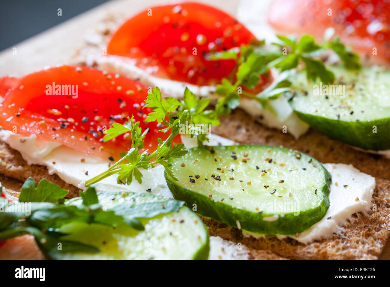 Healthy food, breakfast sandwiches. Finnish rye crisp bread, soft cheese, cucumber, tomato, parsley and black pepper Stock Photo