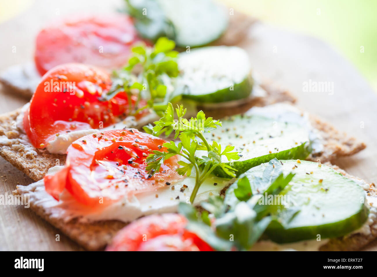 Healthy food, bright sandwiches. Finnish rye crisp bread, soft cheese, cucumber, tomato, parsley and black pepper Stock Photo