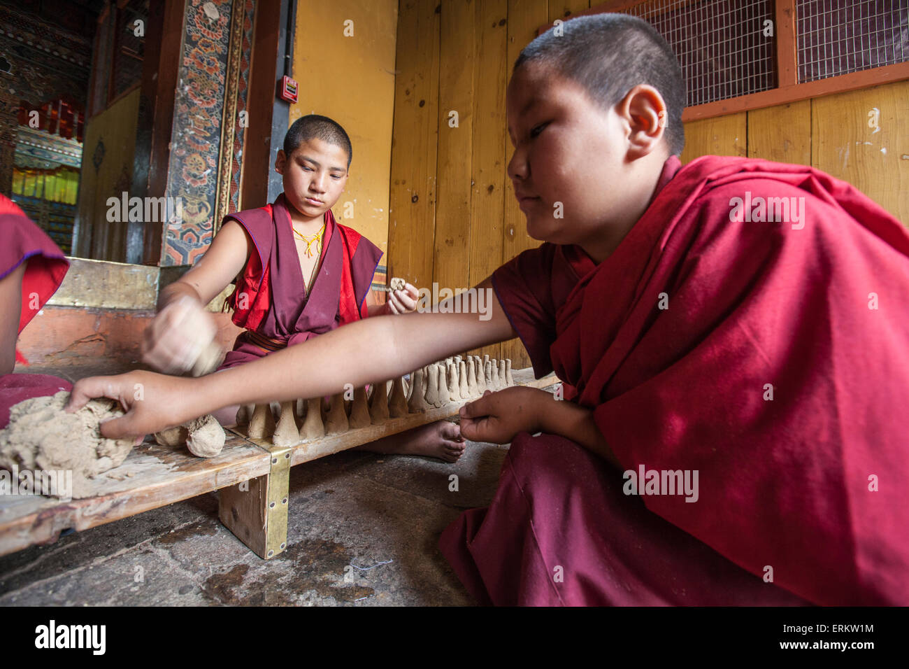 Young Buddhist monk takes clay with his hand to create objects that will be sold, Punakha, Bhutan Stock Photo