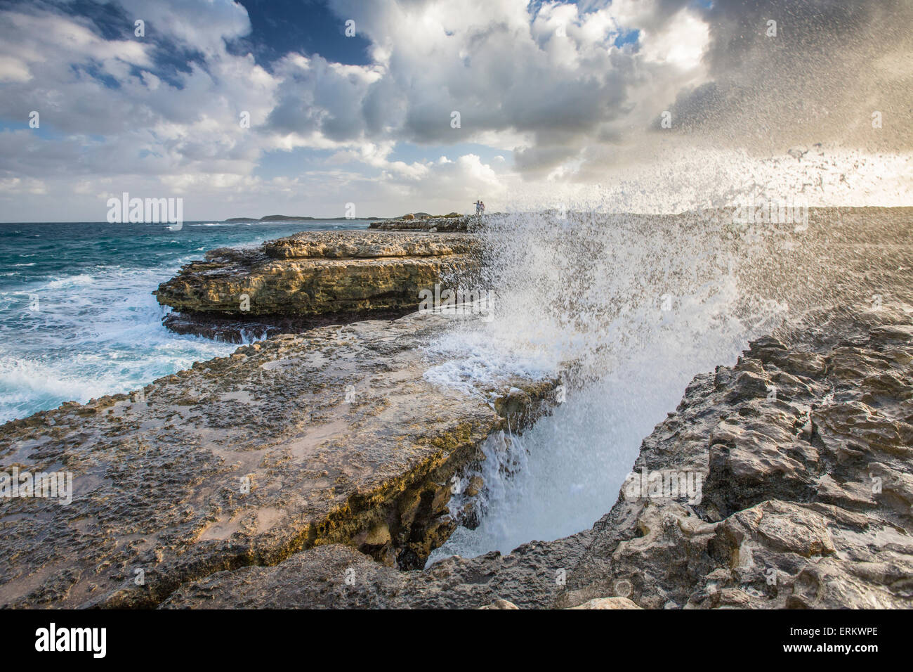 A wave created by the strong wind squirts water over Devils Bridge, a coral bridge created by wind and the power of sea, Antigua Stock Photo