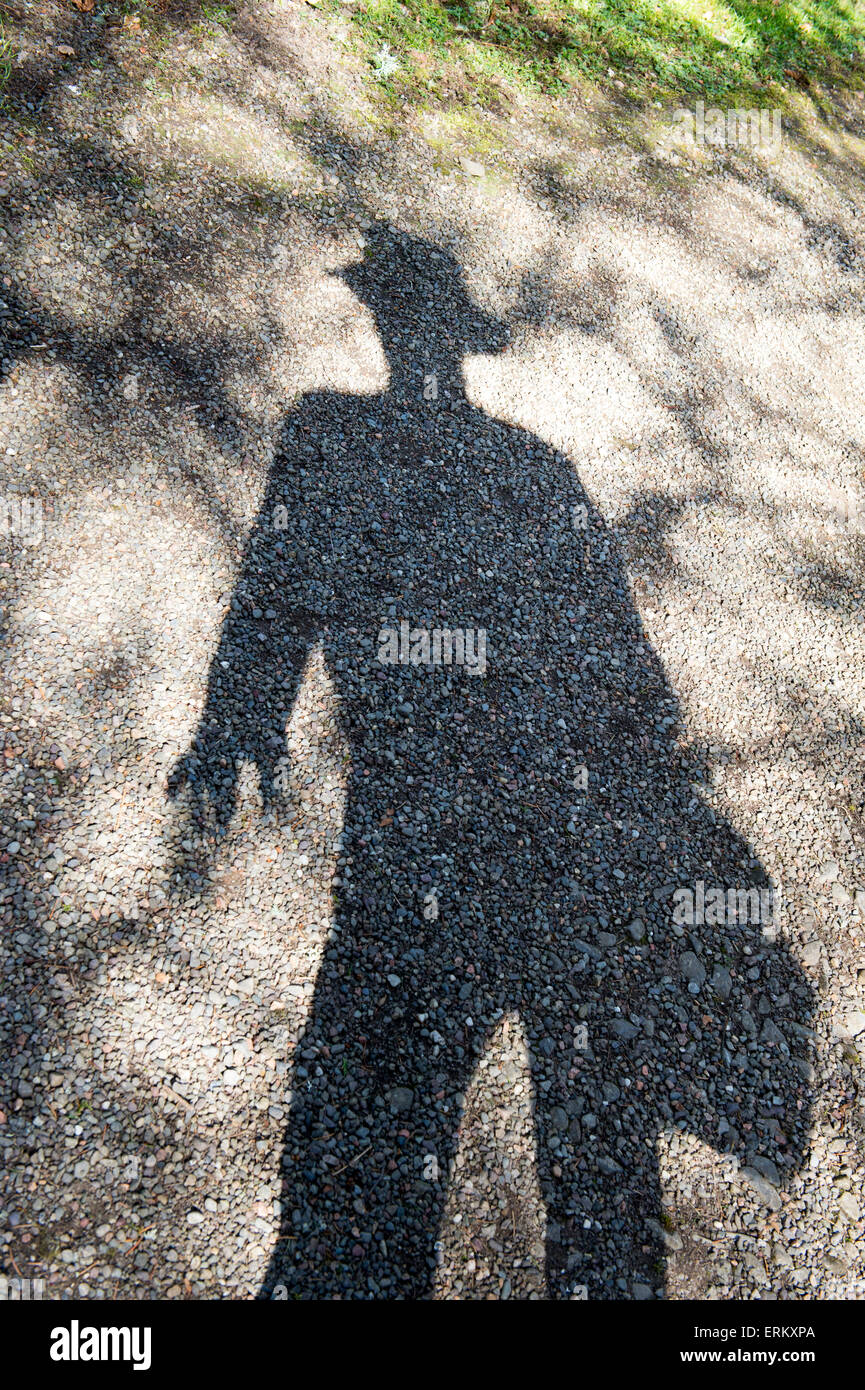 Shadow of a man wearing a brimmed hat in the sunlight. UK Stock Photo