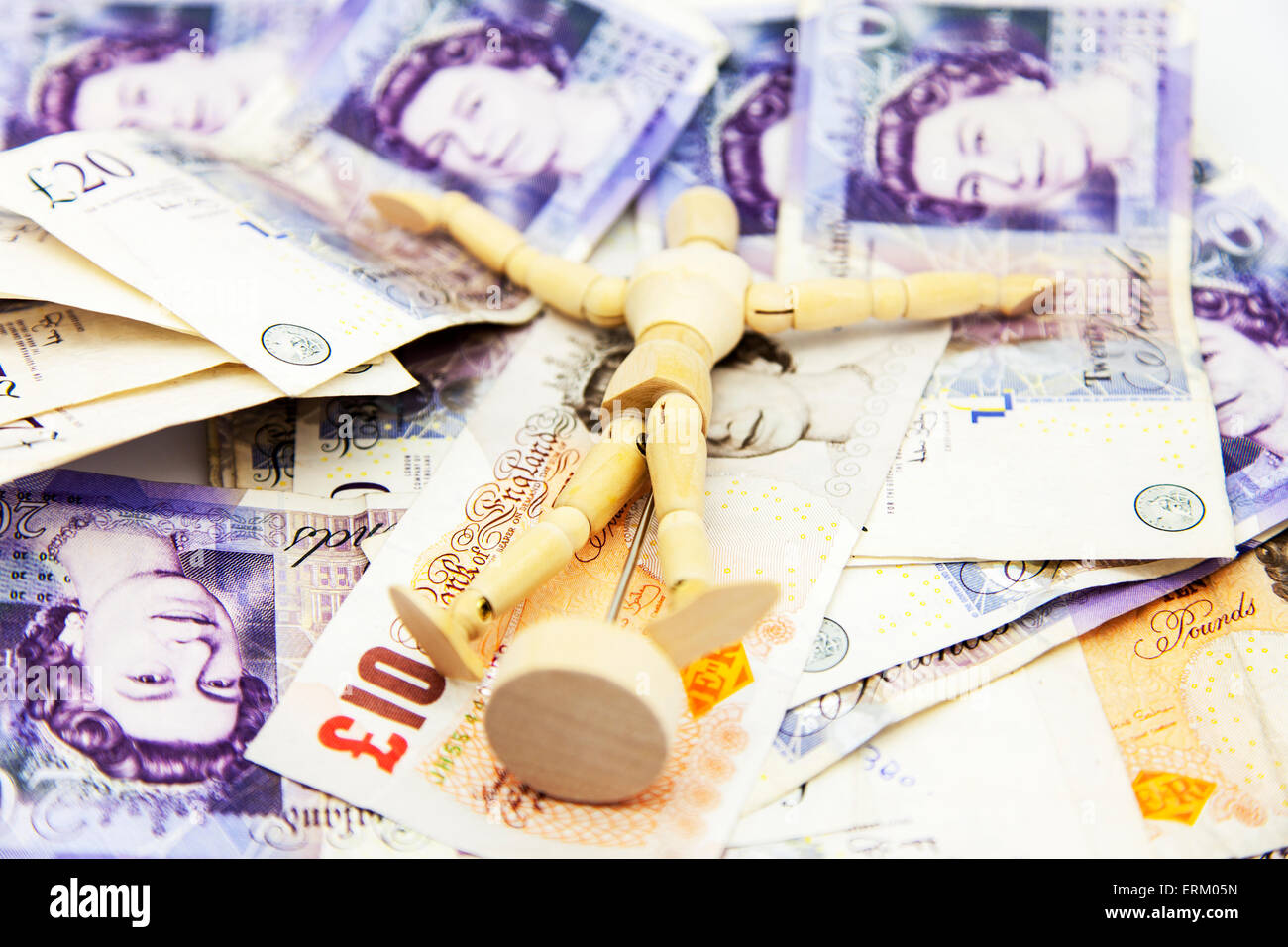 Wooden man rolling in money rich wealthy millionaire wealth wealthy millionaires cash pounds notes pound UK british Stock Photo