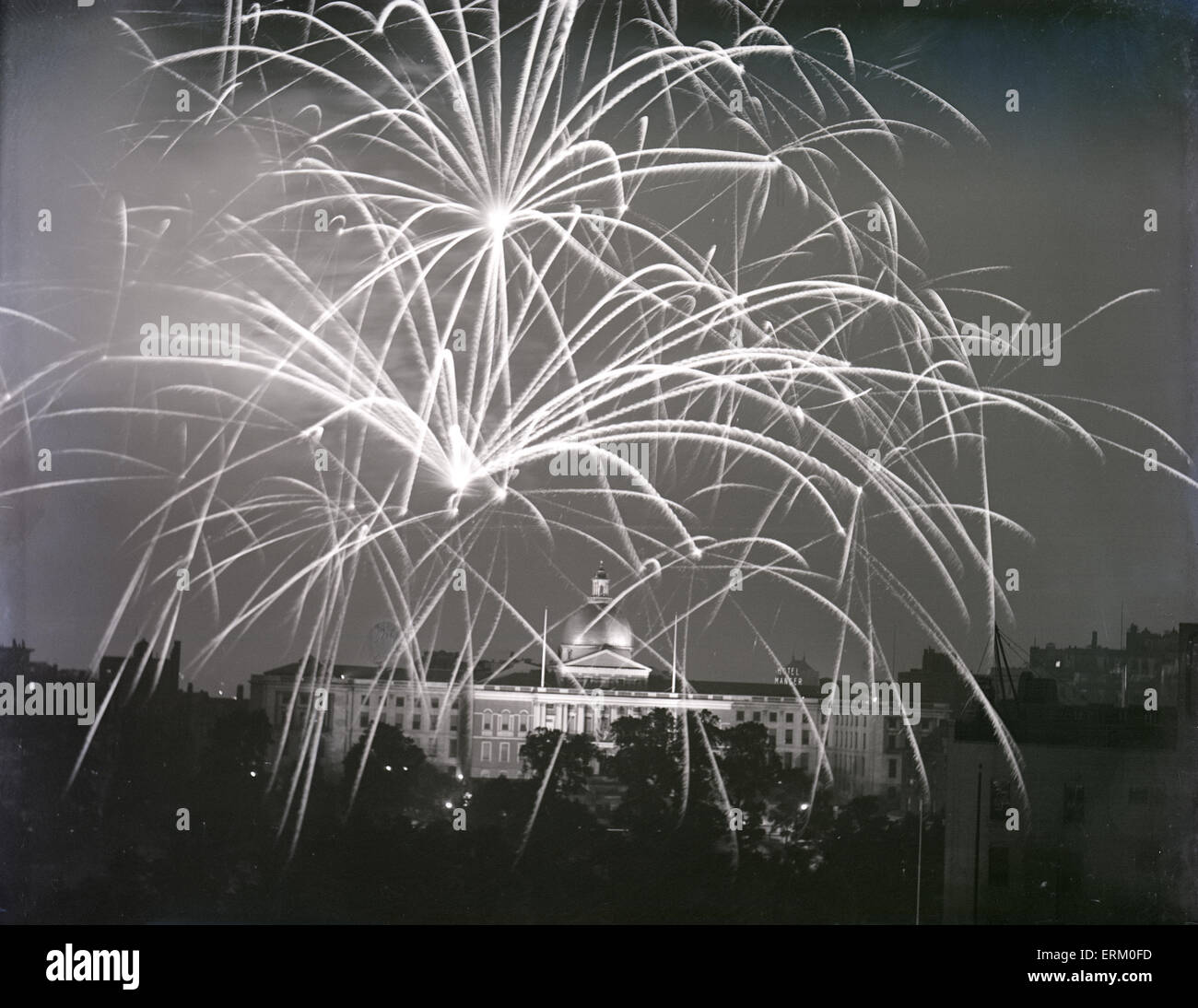 Antique 1930 photograph, July 4th fireworks over the Massachusetts State House in Boston, Massachusetts, USA. The old neon sign for the Hotel Manger is visible in the background. Stock Photo