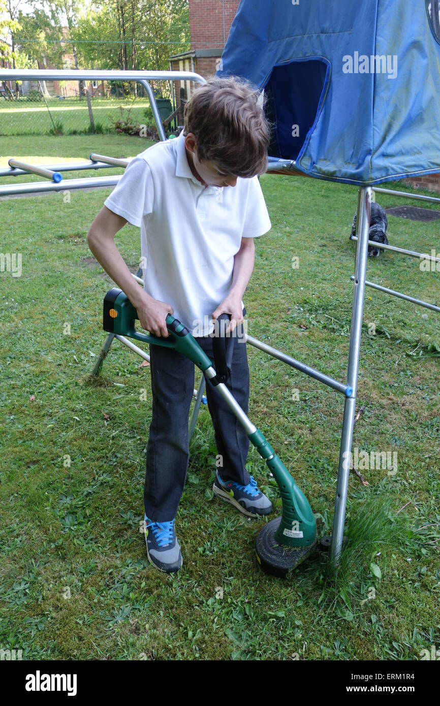Boy aged 10 using battery powered grass strimmer Stock Photo