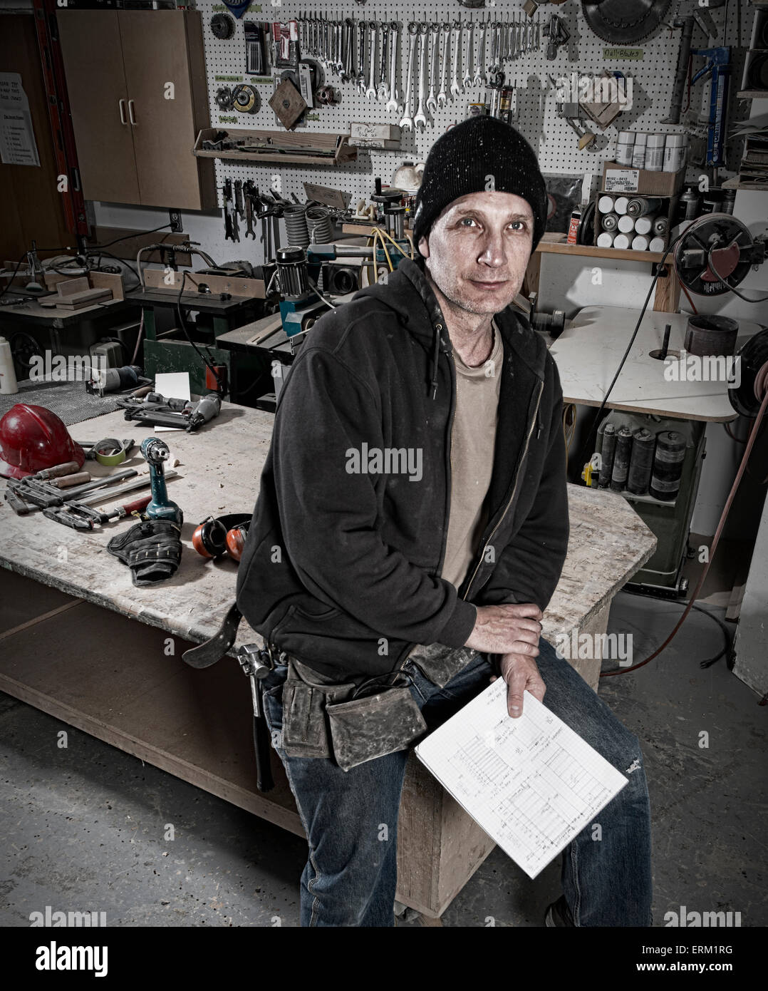A carpenter in his workshop holding paper plans. Stock Photo