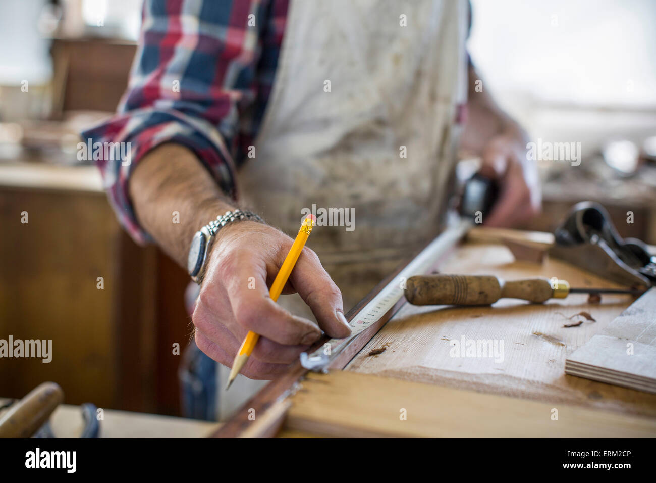 An antique furniture restorer measuring a piece of wood. Stock Photo
