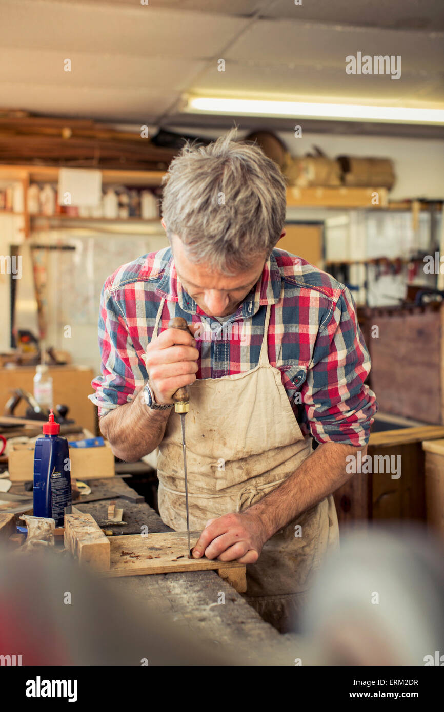 An antique furniture restorer working with a handheld tool on a