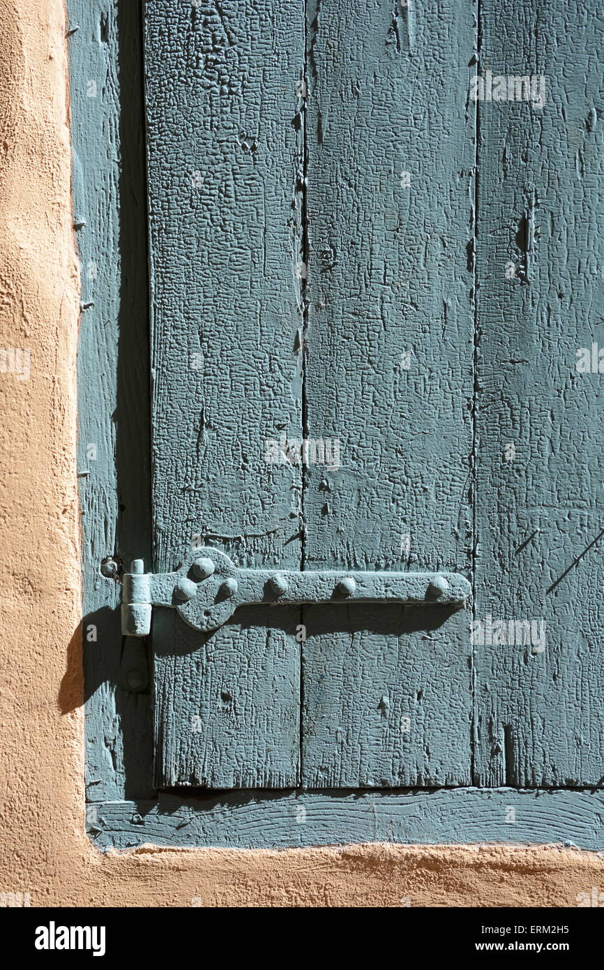 detail of green windows shutter in sunlight on a sand colored wall left Stock Photo