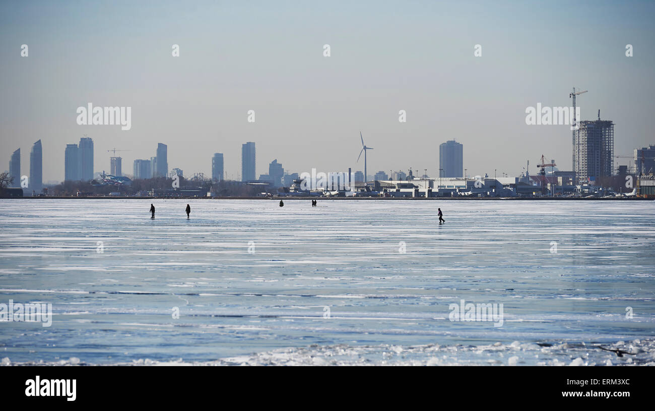 People in the distance on the ice against city skyline from Ward's Island; Toronto, Ontario, Canada Stock Photo