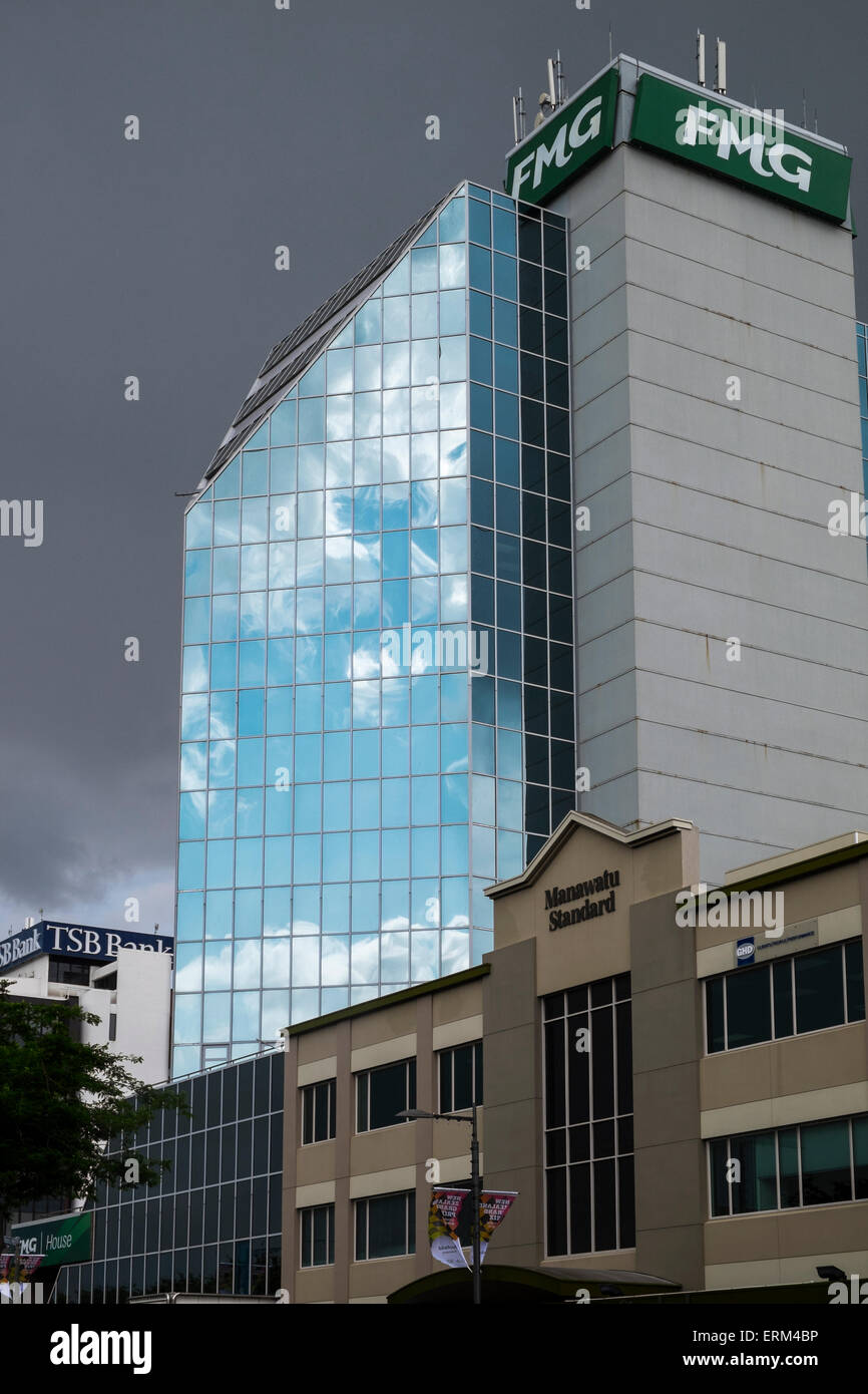 FMG Building reflecting blue sky and fluffy clouds against a grey sky background on a rainy day in Palmerston North, New Zealand Stock Photo