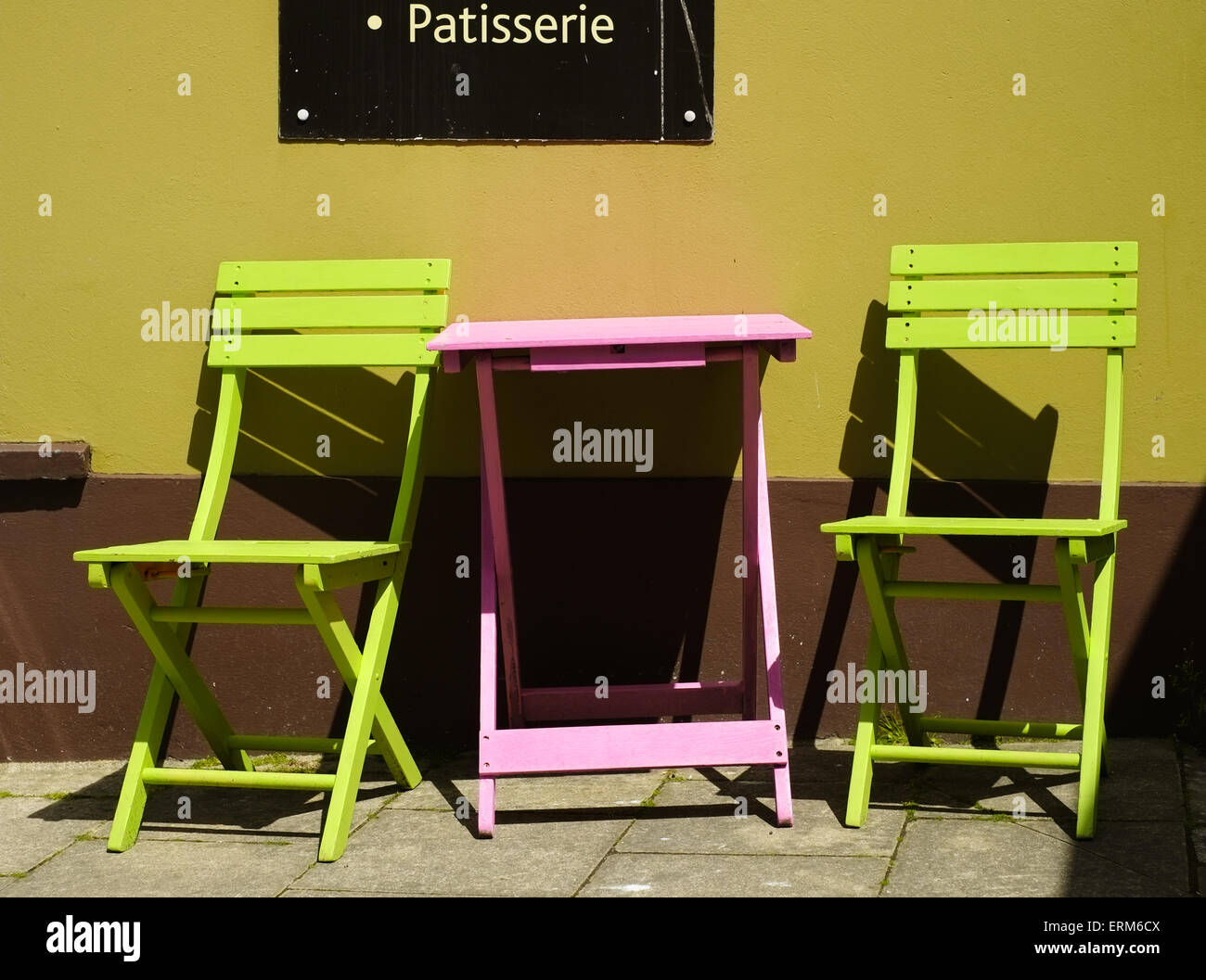 A Pink Table And Two Lime Green Chairs Outside A Cafe On West St