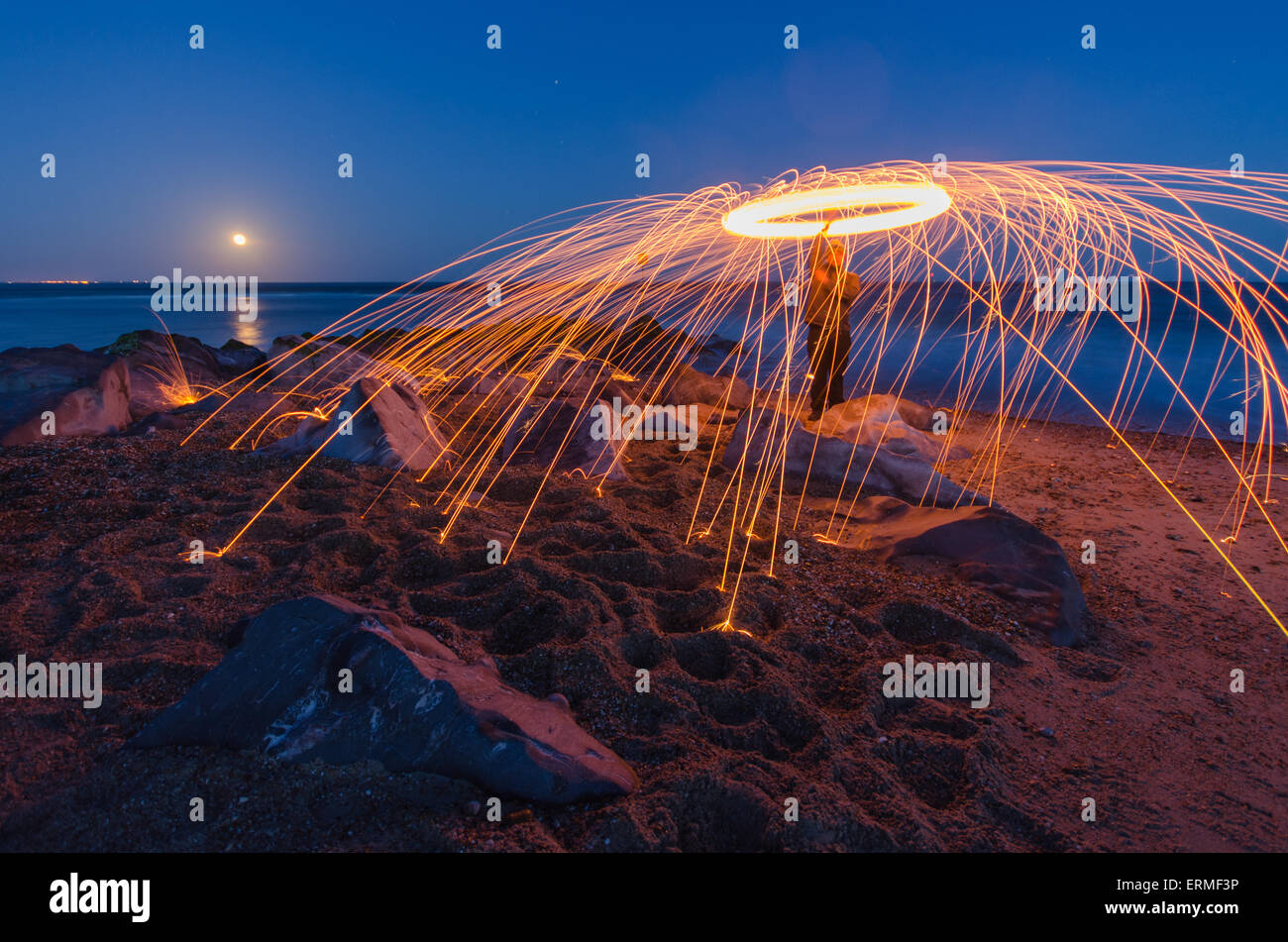 Silhouette of man spinning illuminated wire wool at night, Hayling
